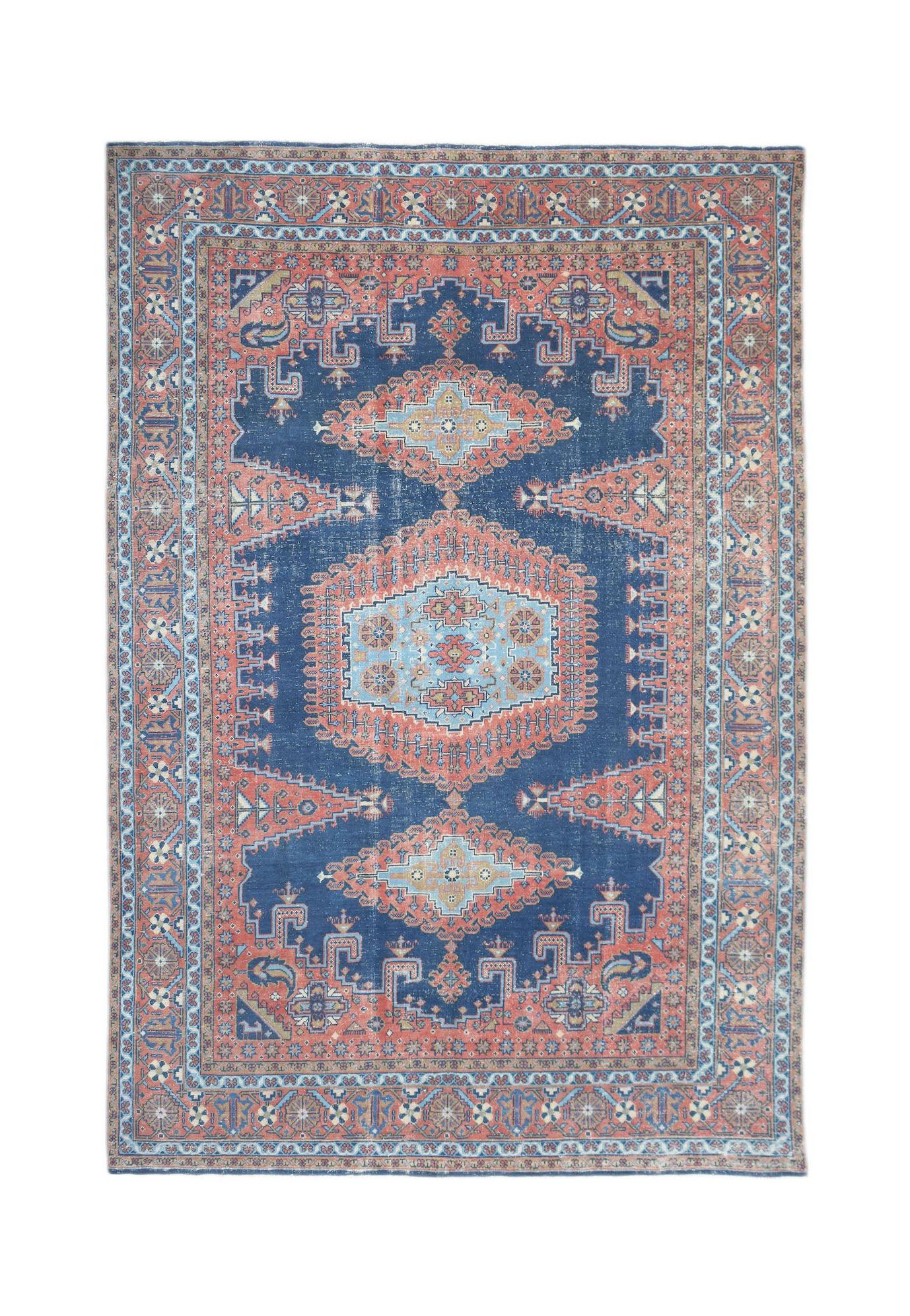 A vintage handwoven Persian rug featuring a central medallion pattern in blue and coral tones.