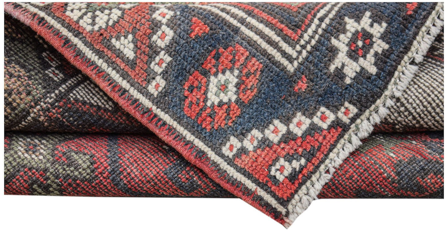 A handwoven vintage Persian runner featuring a geometric pattern in red, blue, and cream wool.