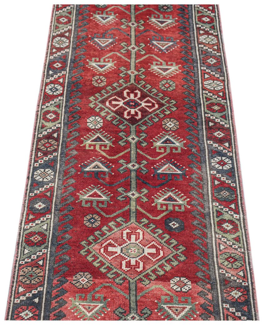 A handwoven vintage Persian runner featuring geometric patterns in red, green, and blue tones.