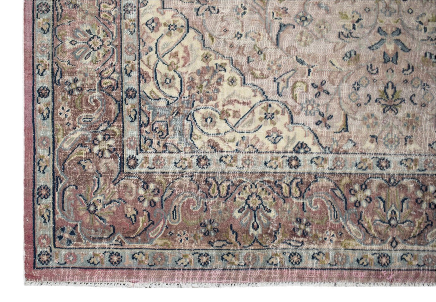 A vintage Persian Kerman rug featuring a dusty pink field with intricate floral patterns.