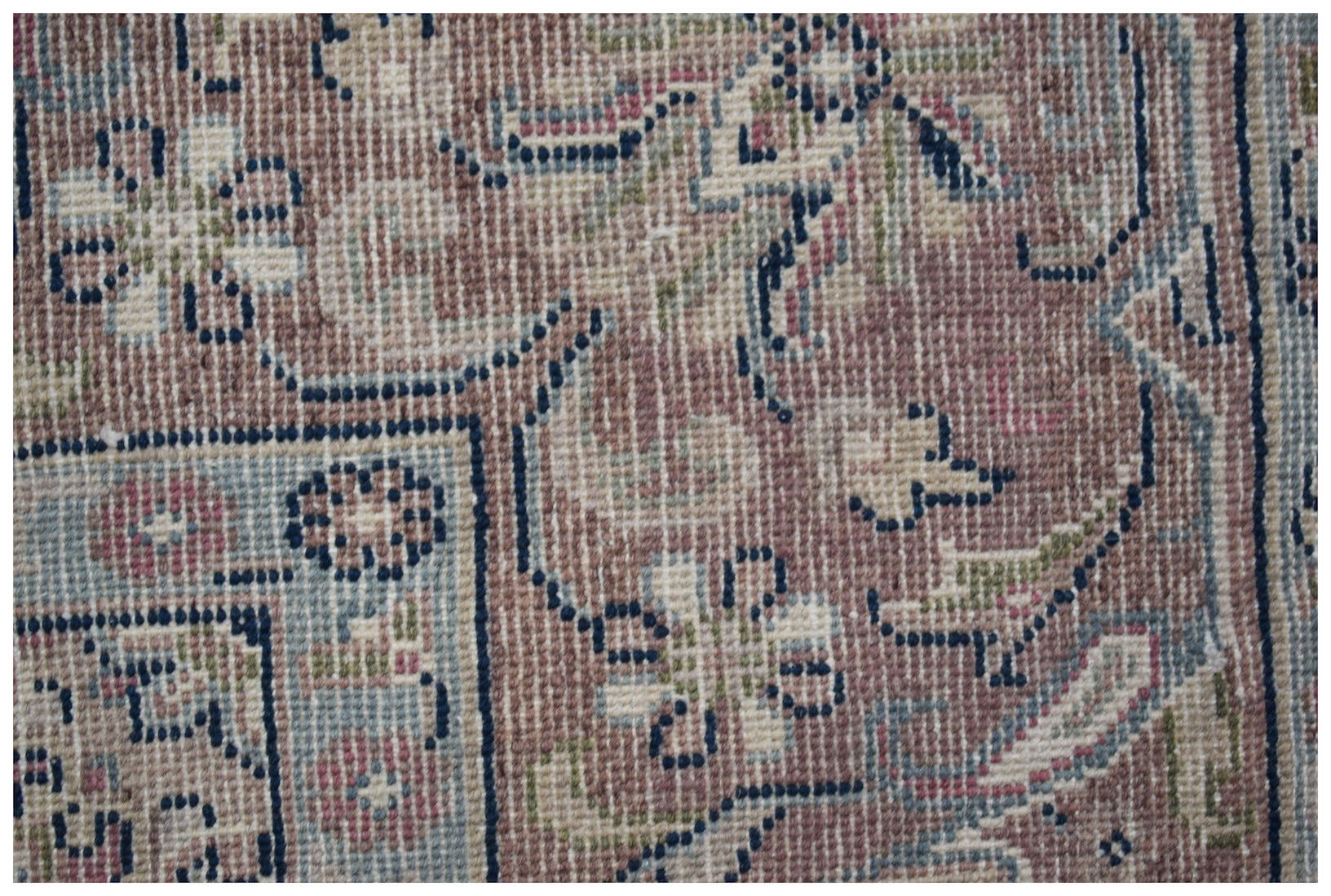 A close-up of a vintage Persian Kerman rug featuring intricate floral patterns in muted tones.