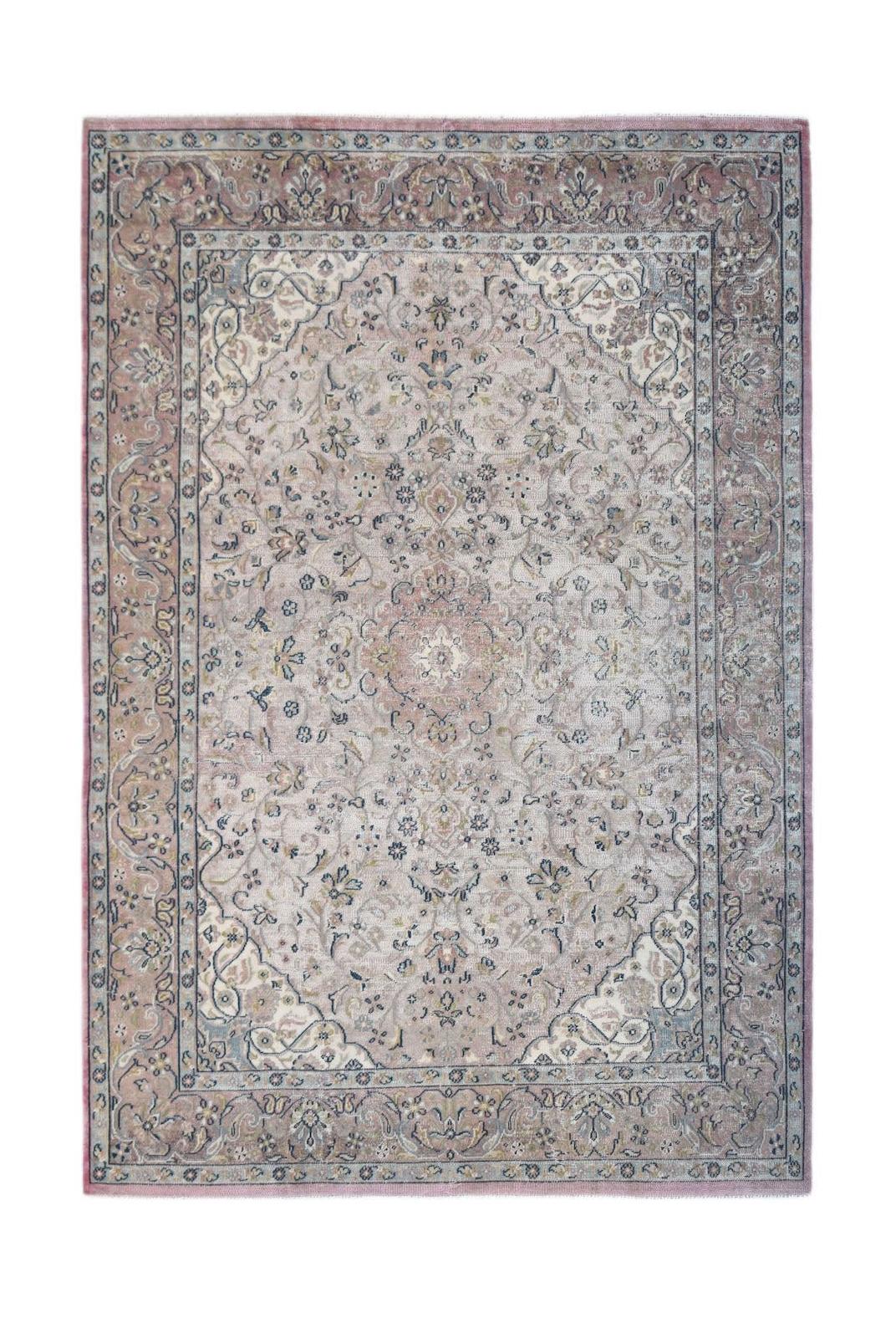 A vintage Persian Kerman rug featuring a central medallion and intricate floral patterns in soft hues.