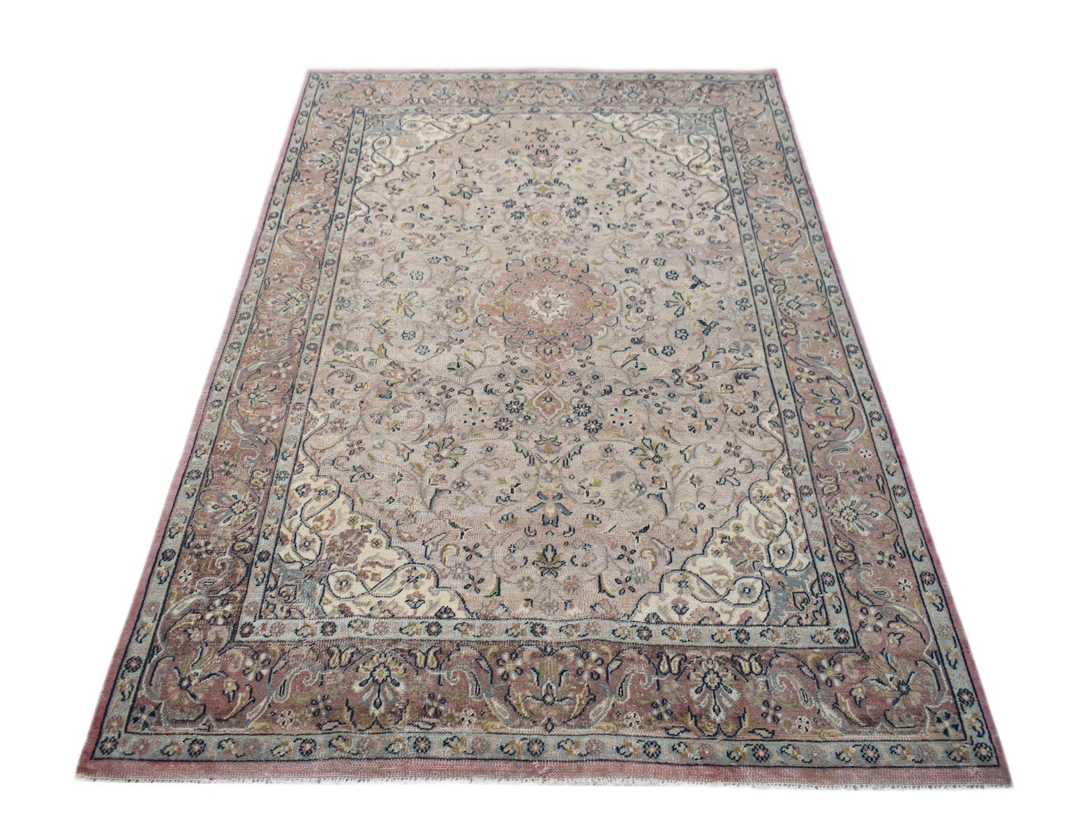 A vintage Persian Kerman rug featuring a central medallion and intricate floral patterns in pink.