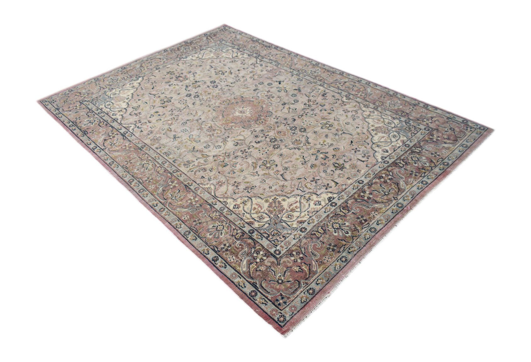 A vintage Persian Kerman rug featuring a central medallion and intricate floral patterns in soft pink.