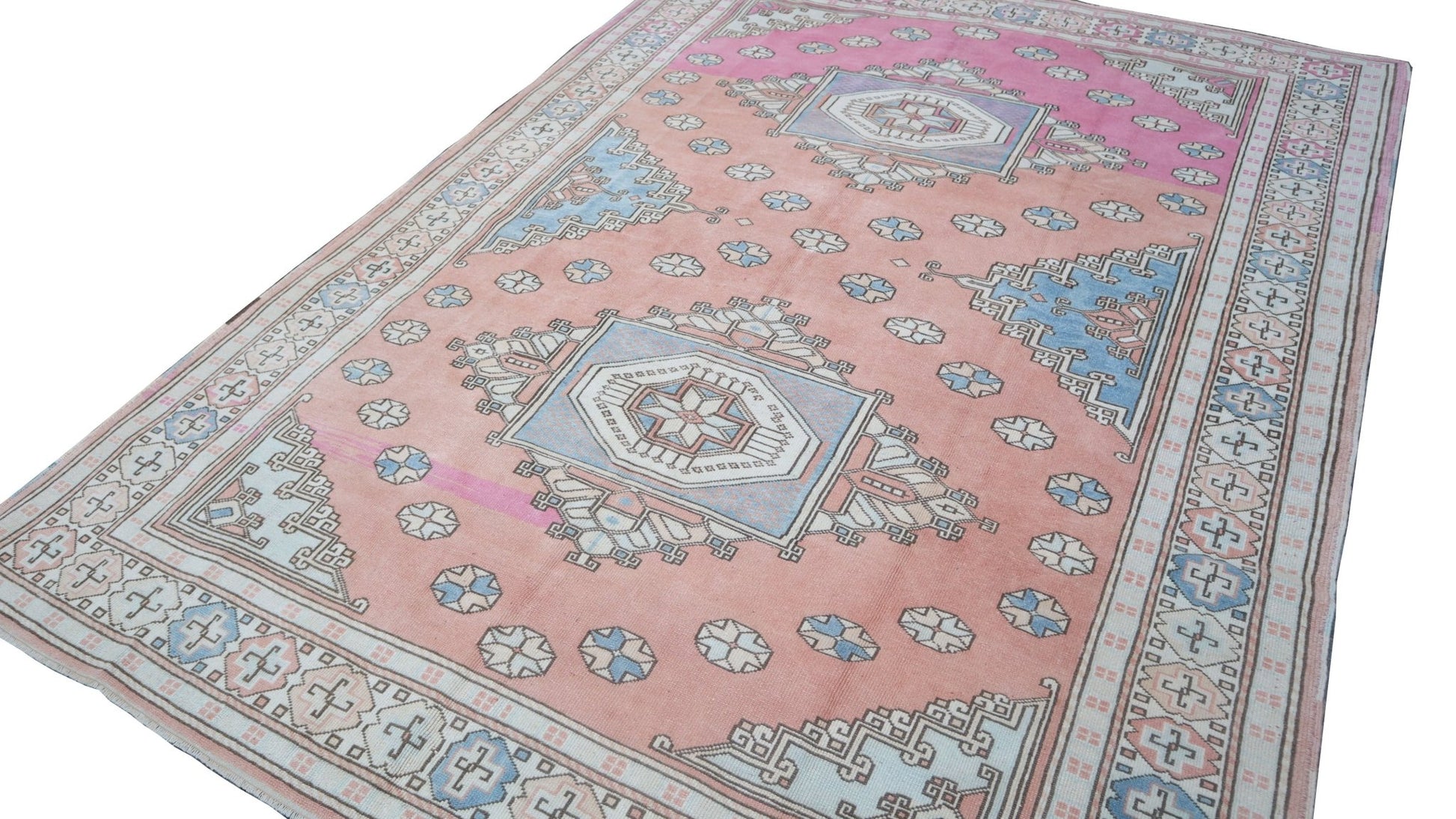 A vintage handmade Turkish Anatolian rug featuring a pink field with blue geometric tribal motifs.