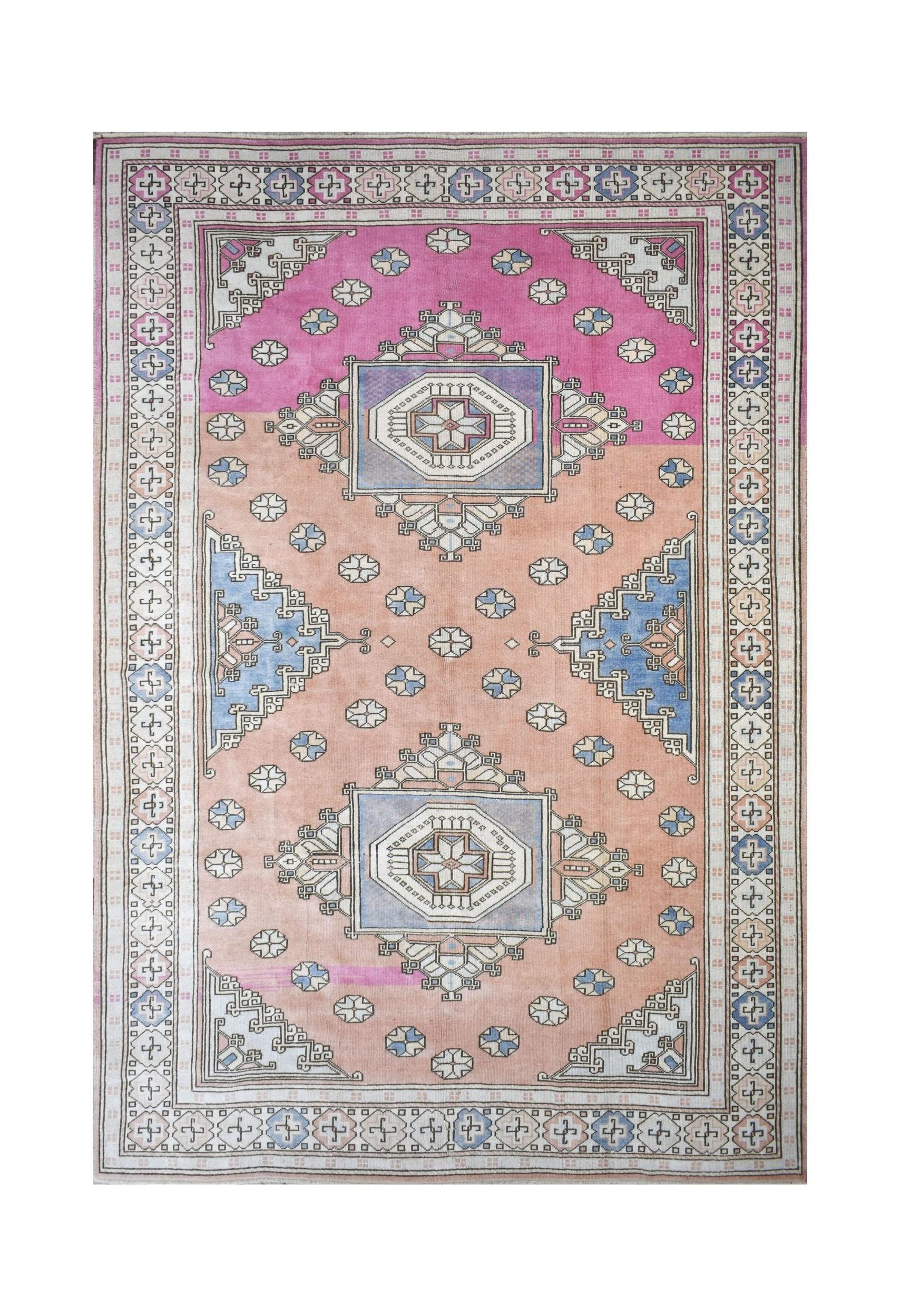 A vintage handmade Turkish Anatolian rug featuring a geometric tribal pattern in pink and peach.