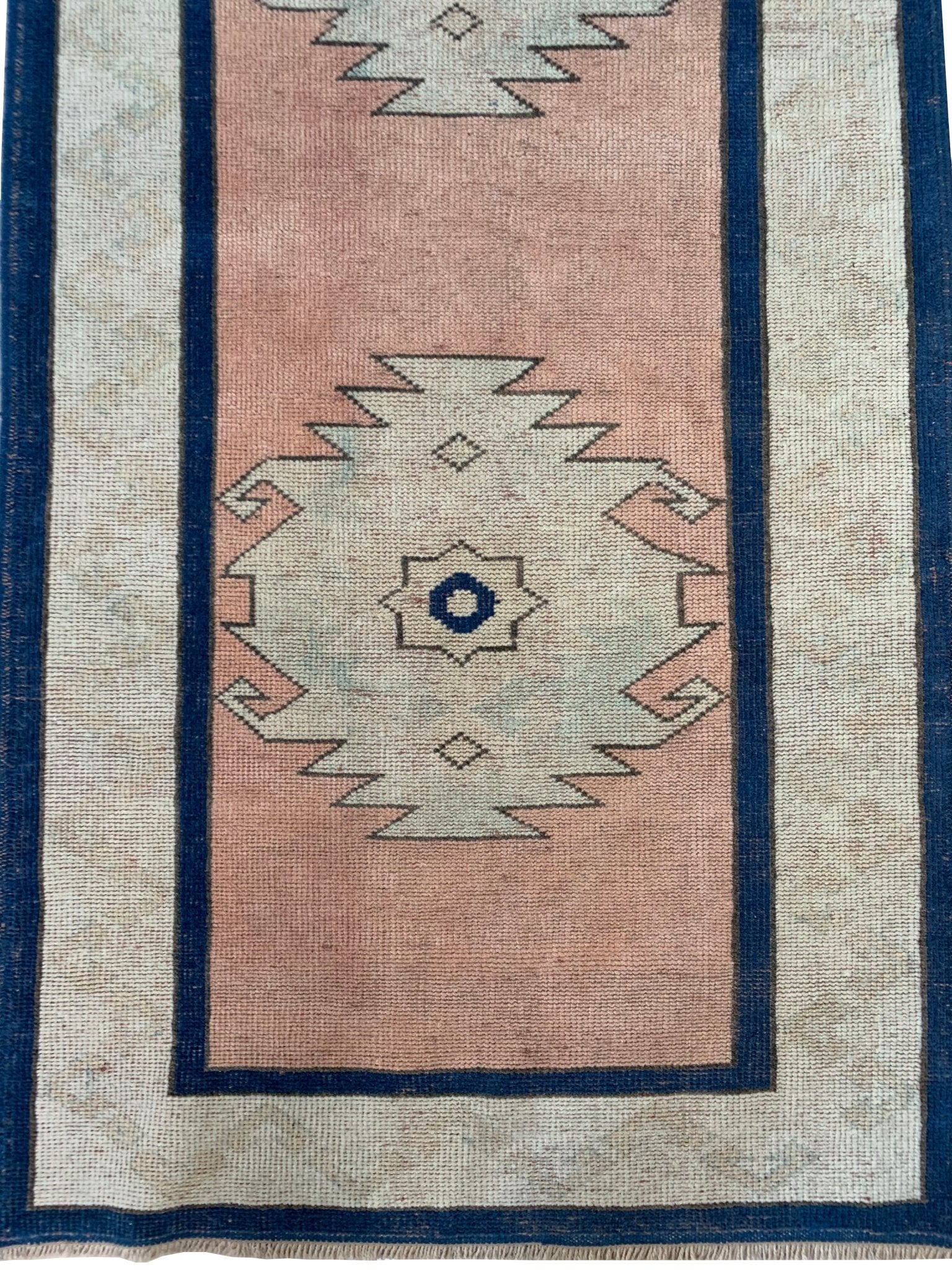 A vintage Turkish Oushak runner featuring a pink field with tribal motifs and blue borders.