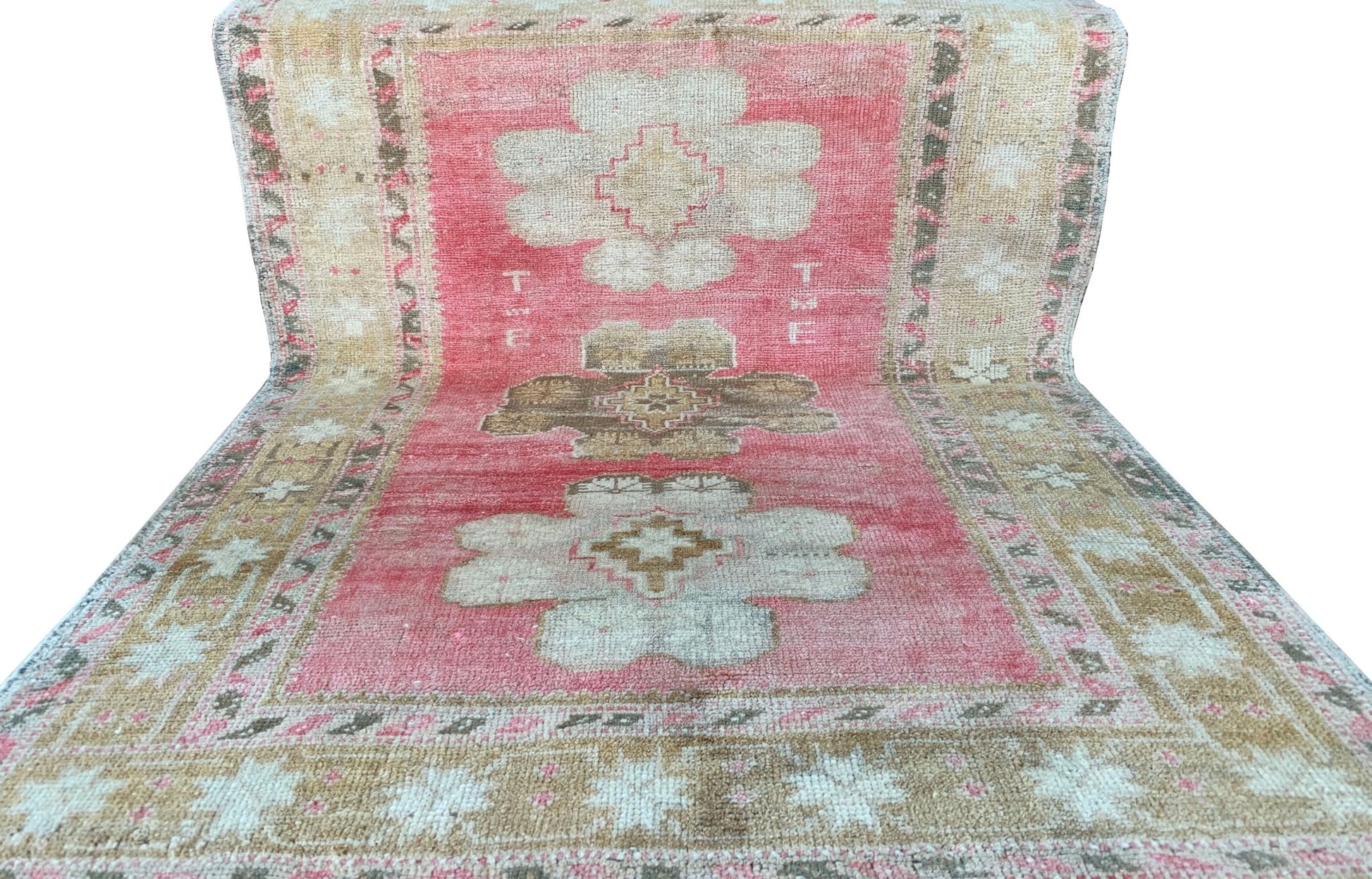A vintage Turkish Oushak rug featuring a pink field with tribal floral motifs and beige borders.