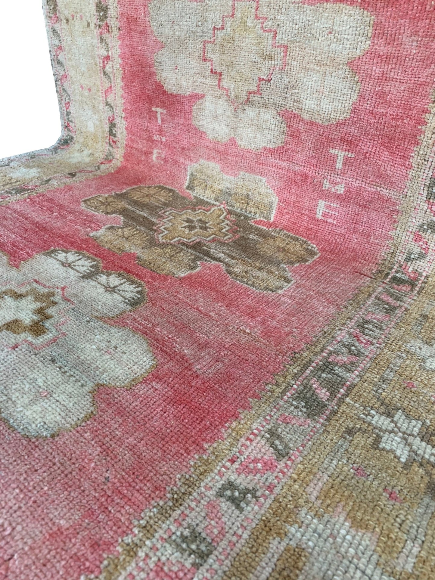 A vintage handmade Turkish Oushak rug featuring a pink field with tribal floral motifs.