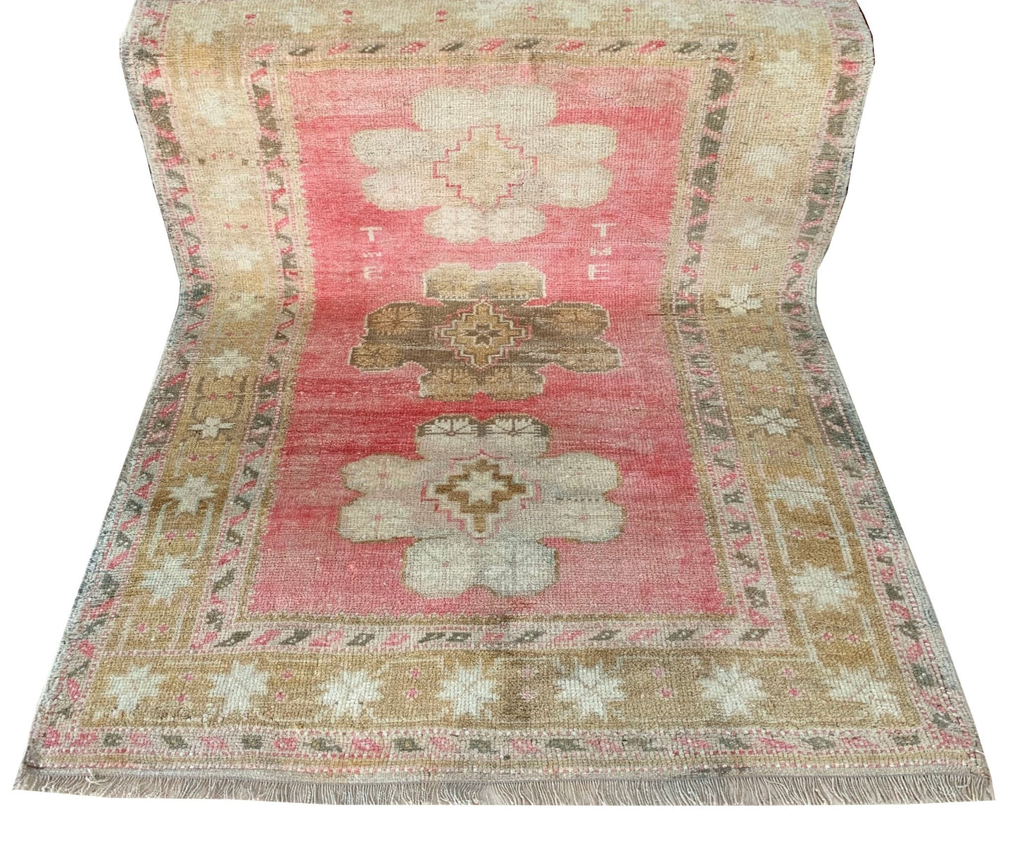 A vintage handmade Turkish Oushak rug featuring a pink field with tribal floral motifs.