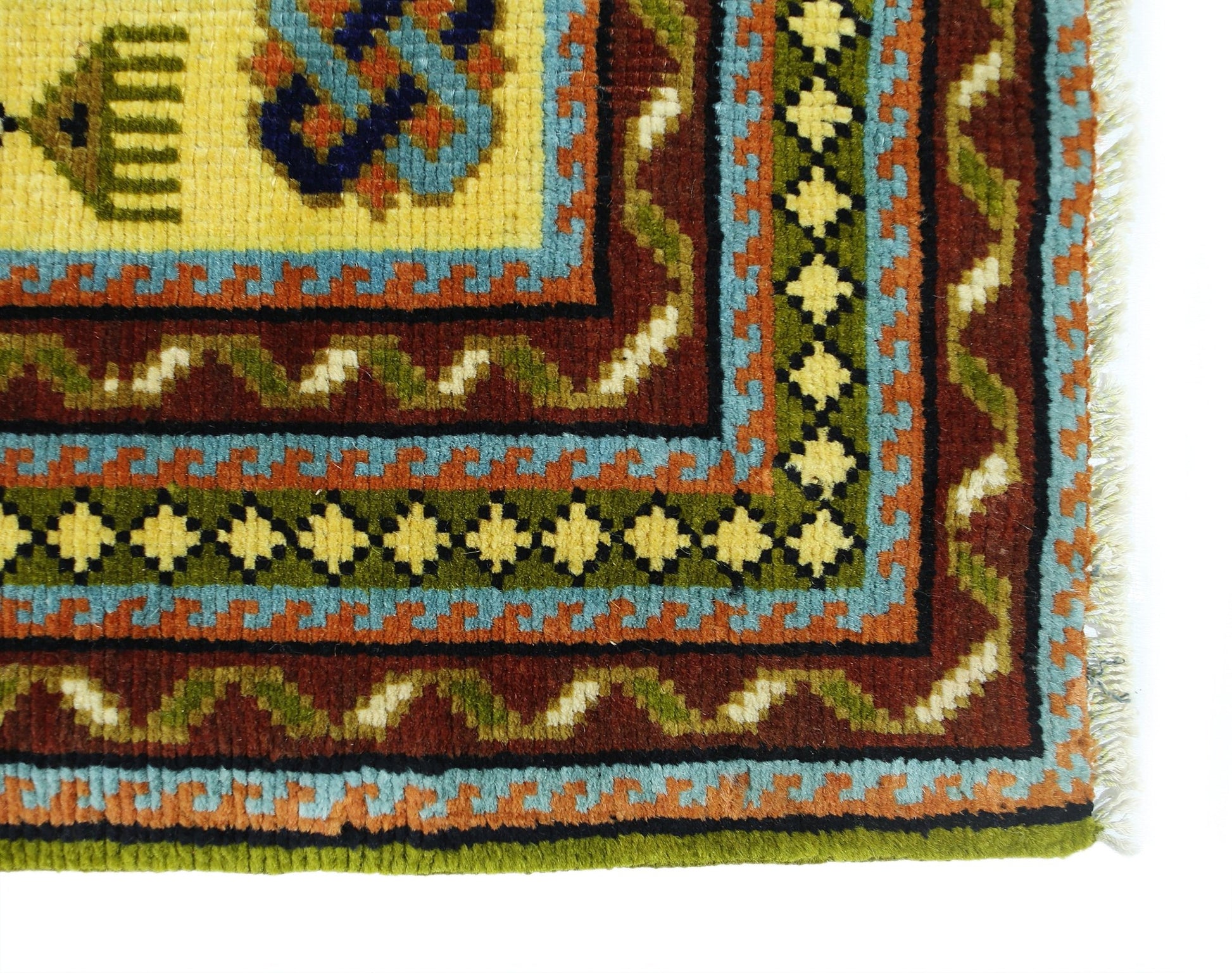 A corner view of a vintage Turkish runner featuring geometric patterns in yellow, blue, and red.