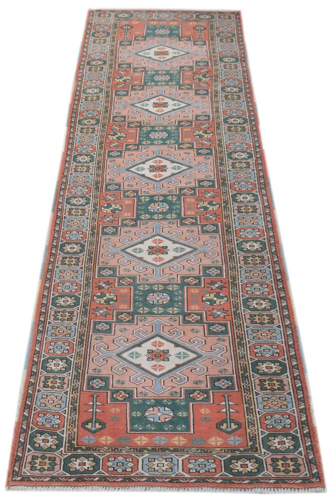 A handwoven vintage Turkish Kars runner featuring geometric diamond motifs in coral and teal.