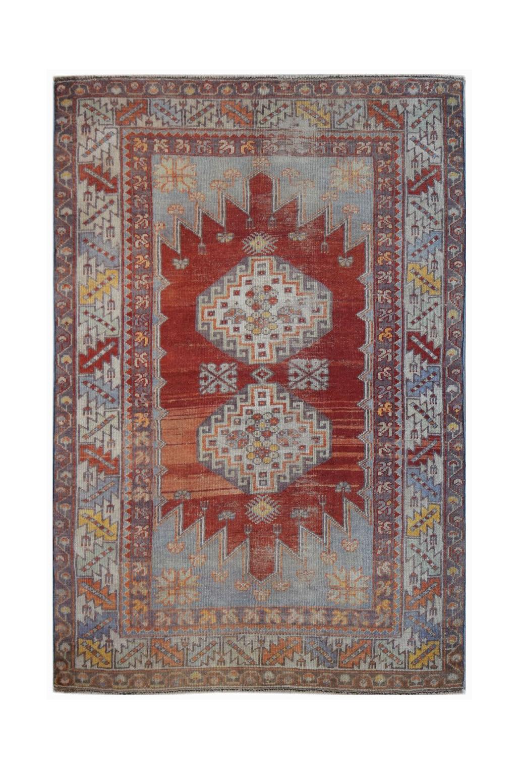 A vintage Turkish Kula rug featuring geometric patterns in red, blue, and yellow tones.