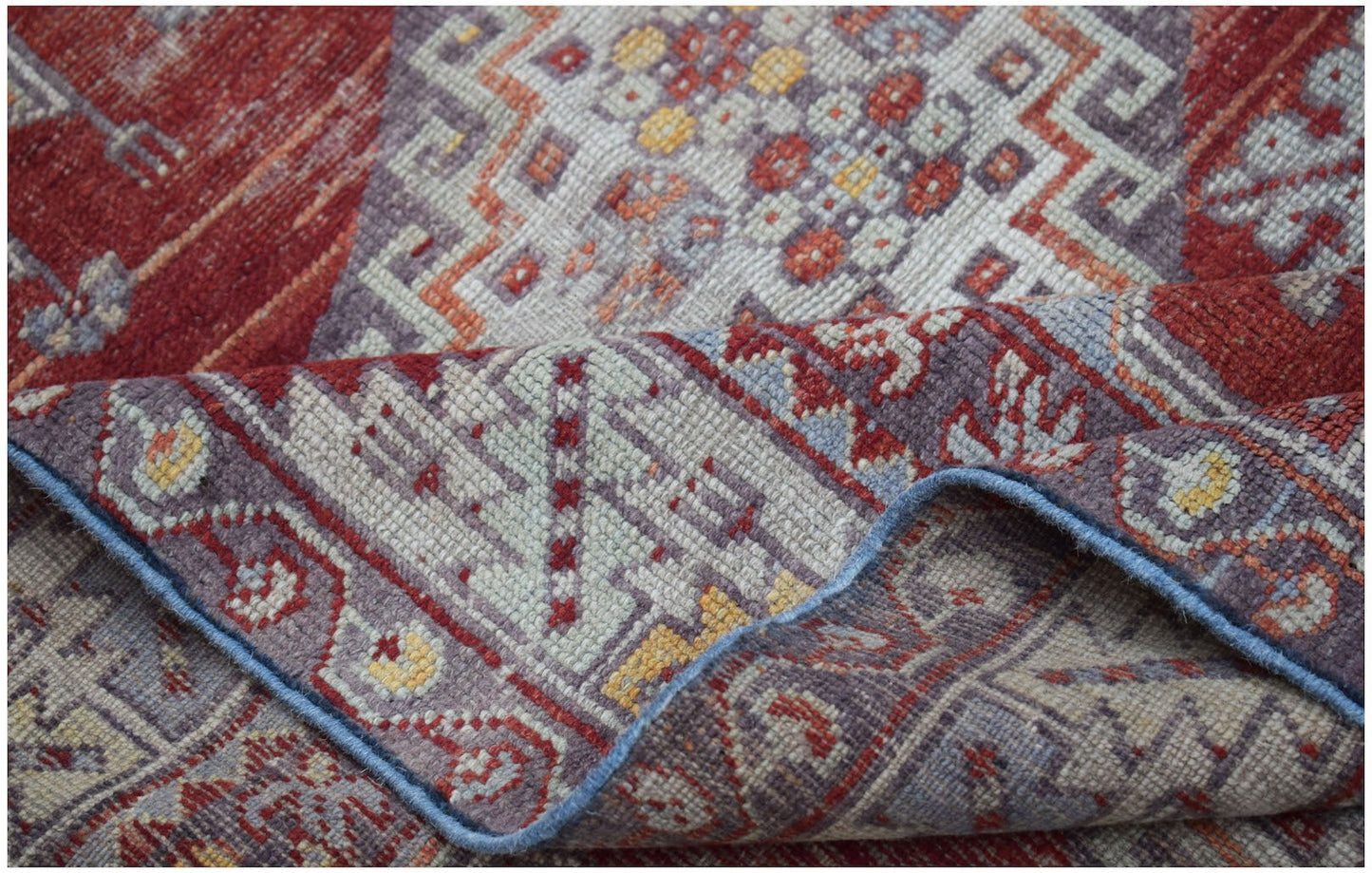 A vintage Turkish Kula rug featuring geometric patterns in red, blue, and yellow wool.