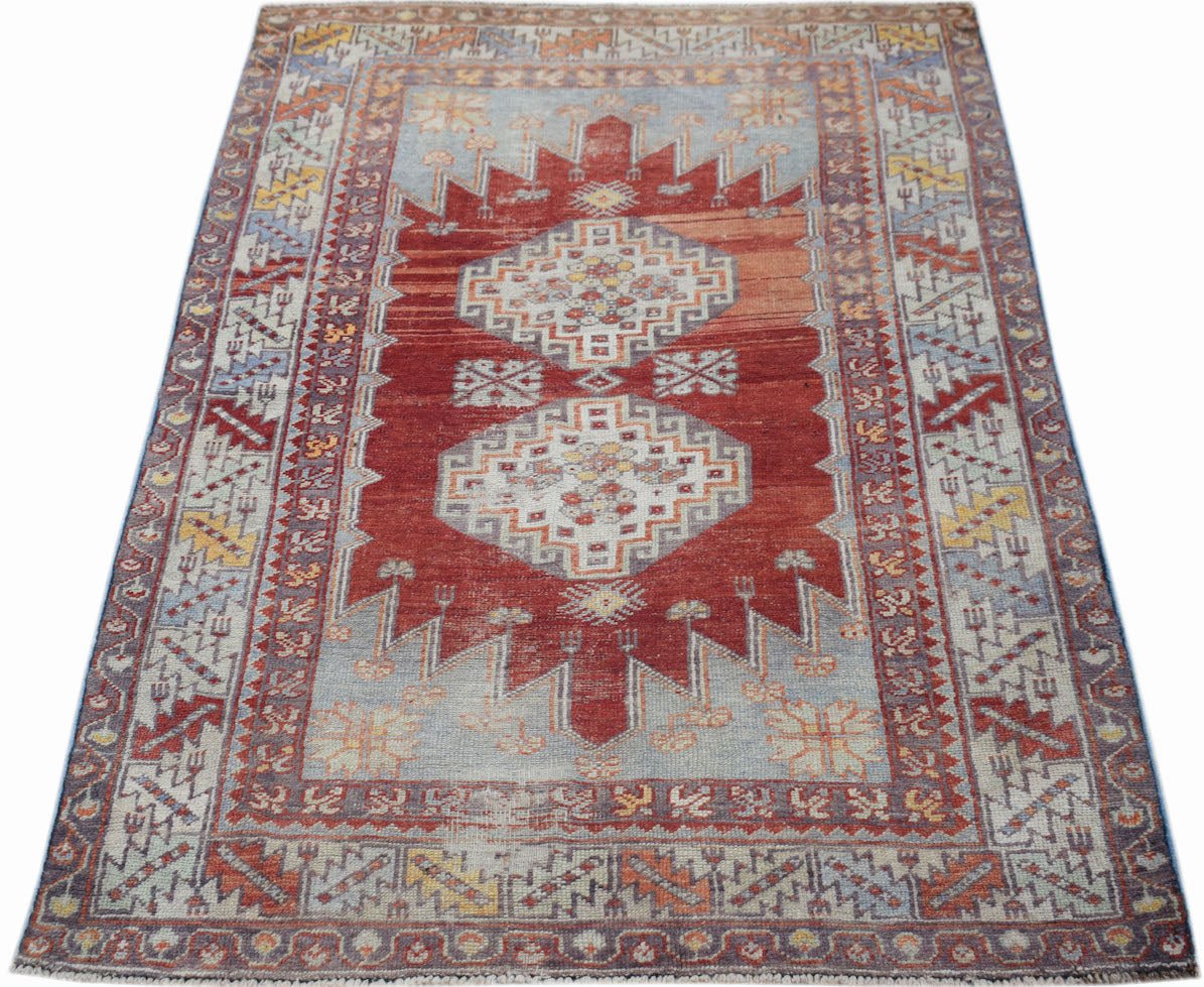 A vintage handmade Turkish Kula rug featuring geometric patterns in red, blue, and yellow tones.