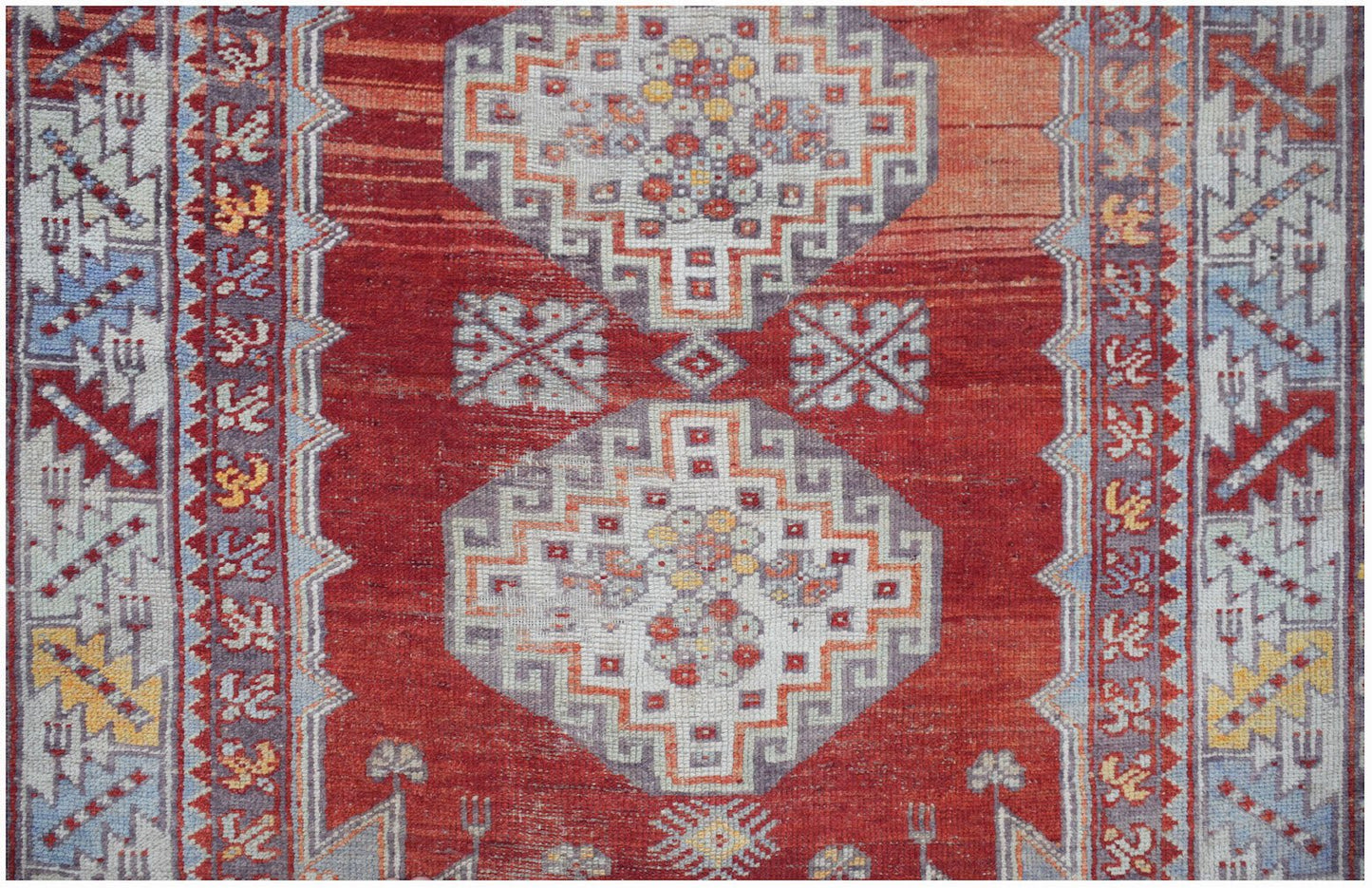 A vintage Turkish Kula rug featuring geometric patterns in red, orange, and blue tones.