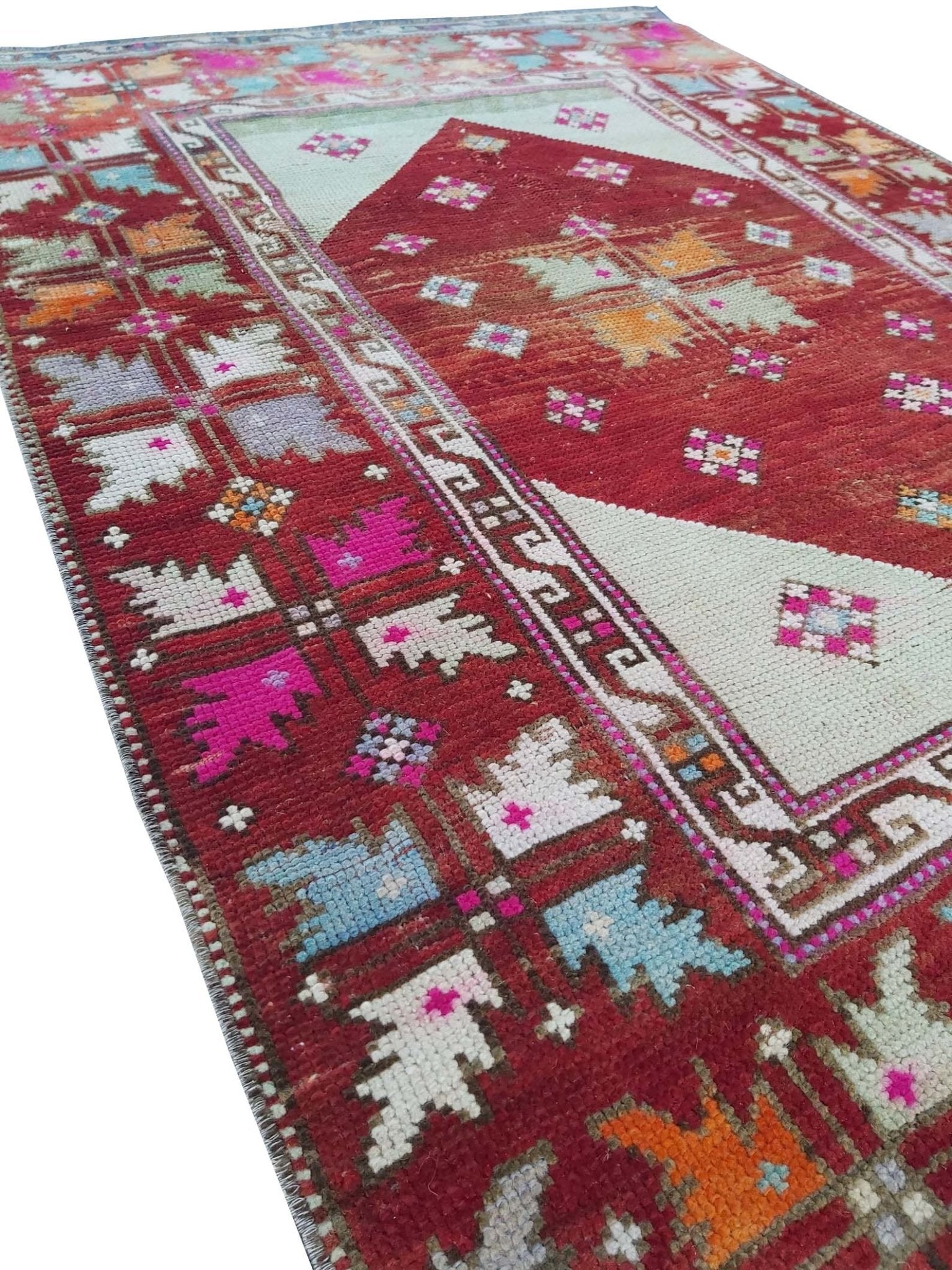A vintage handmade Turkish Kula rug featuring geometric patterns in red, pink, and blue tones.