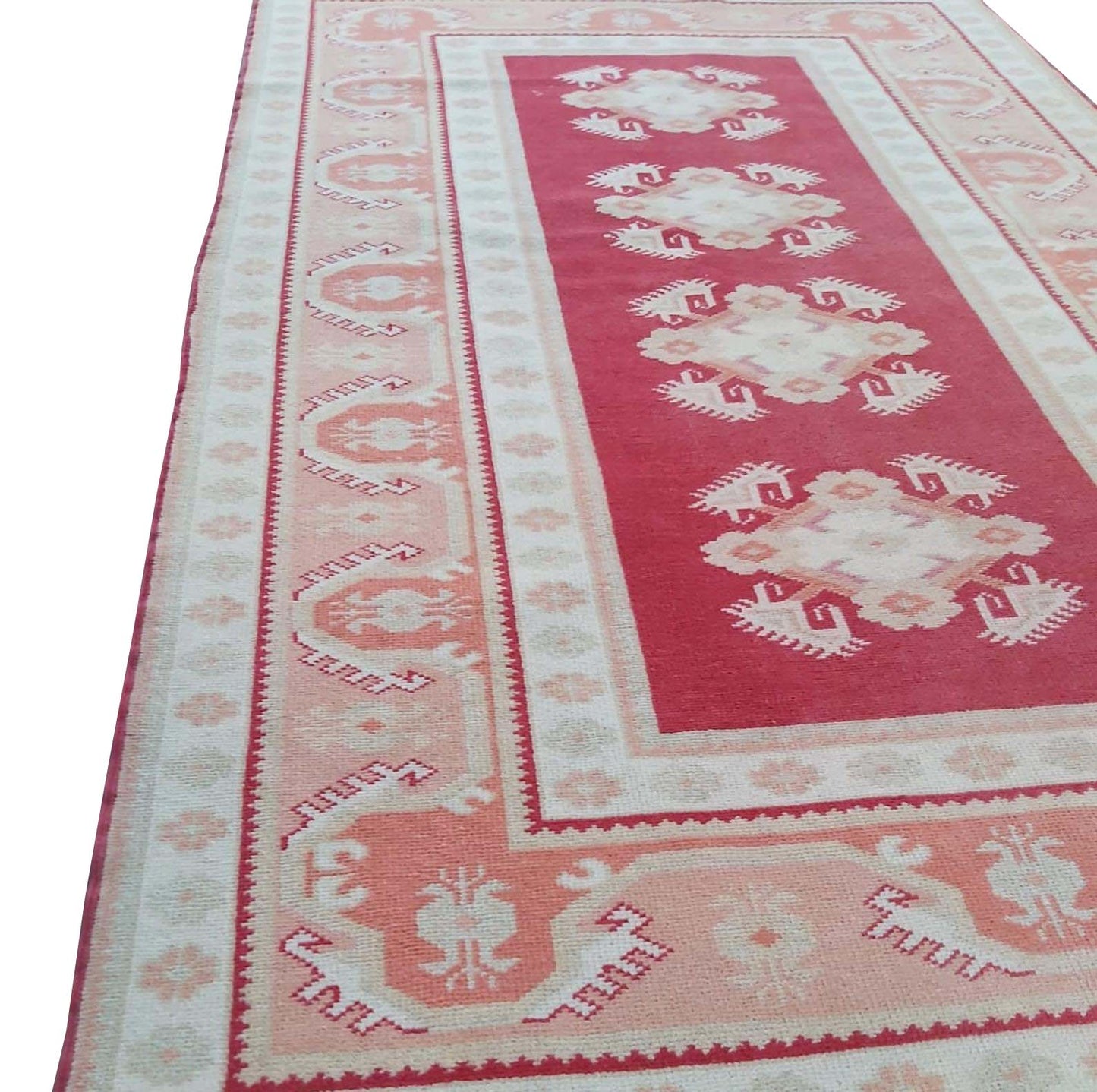 A vintage Turkish Milas rug featuring geometric patterns in red, cream, and soft pink tones.