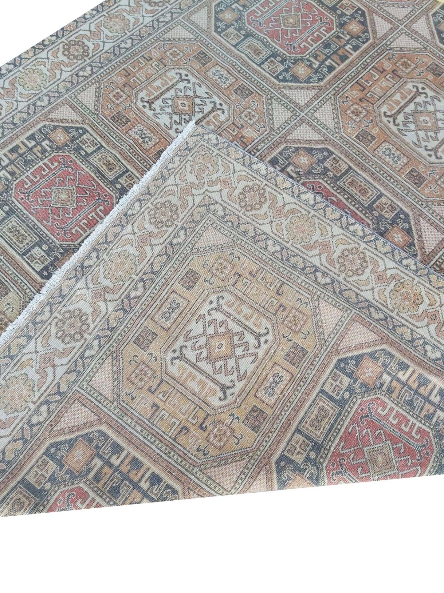 A vintage handmade Turkish Oushak rug featuring a geometric pattern in muted red and beige tones.