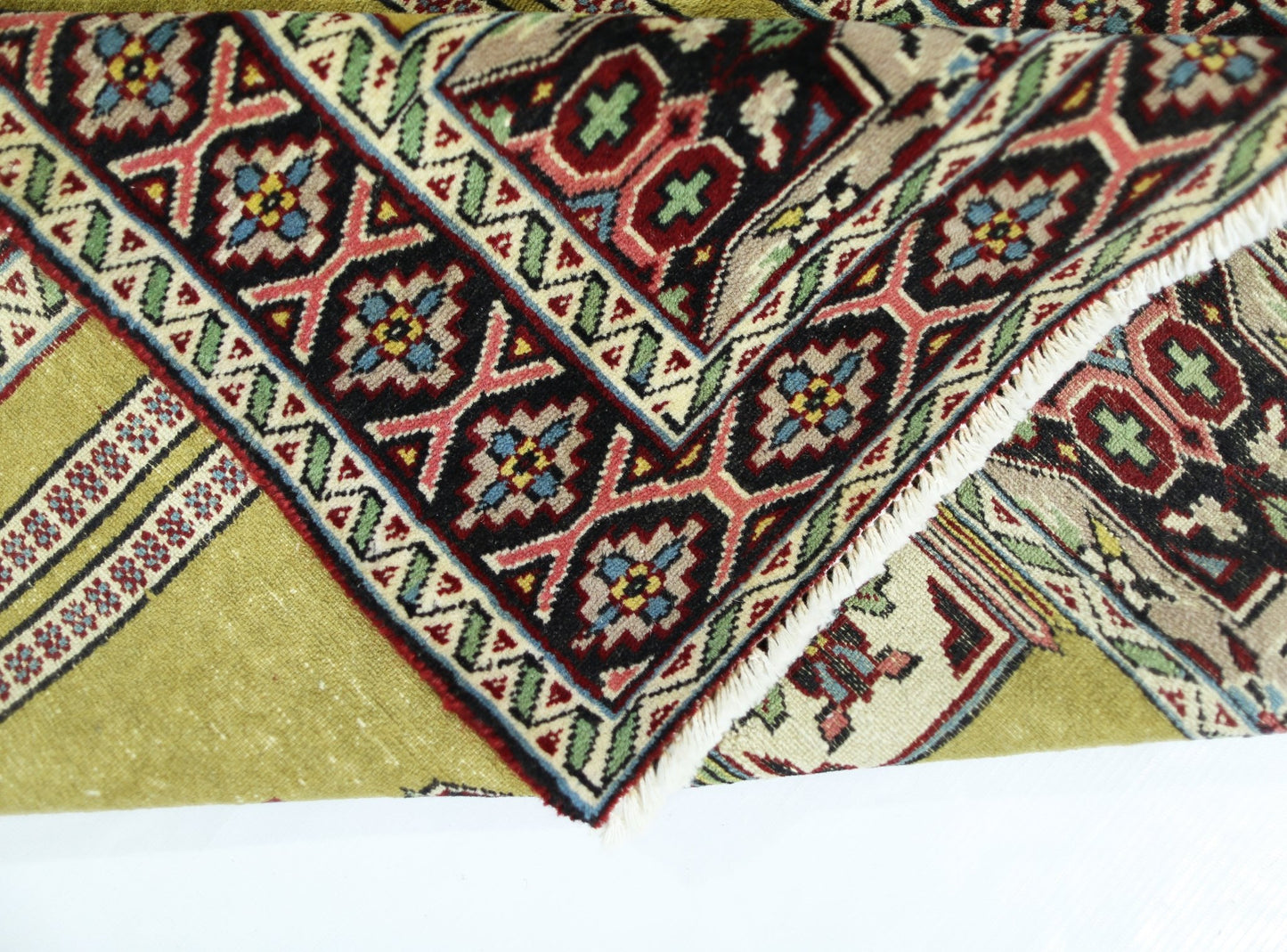 A vintage handmade Turkish prayer rug featuring a geometric floral border and a green field.