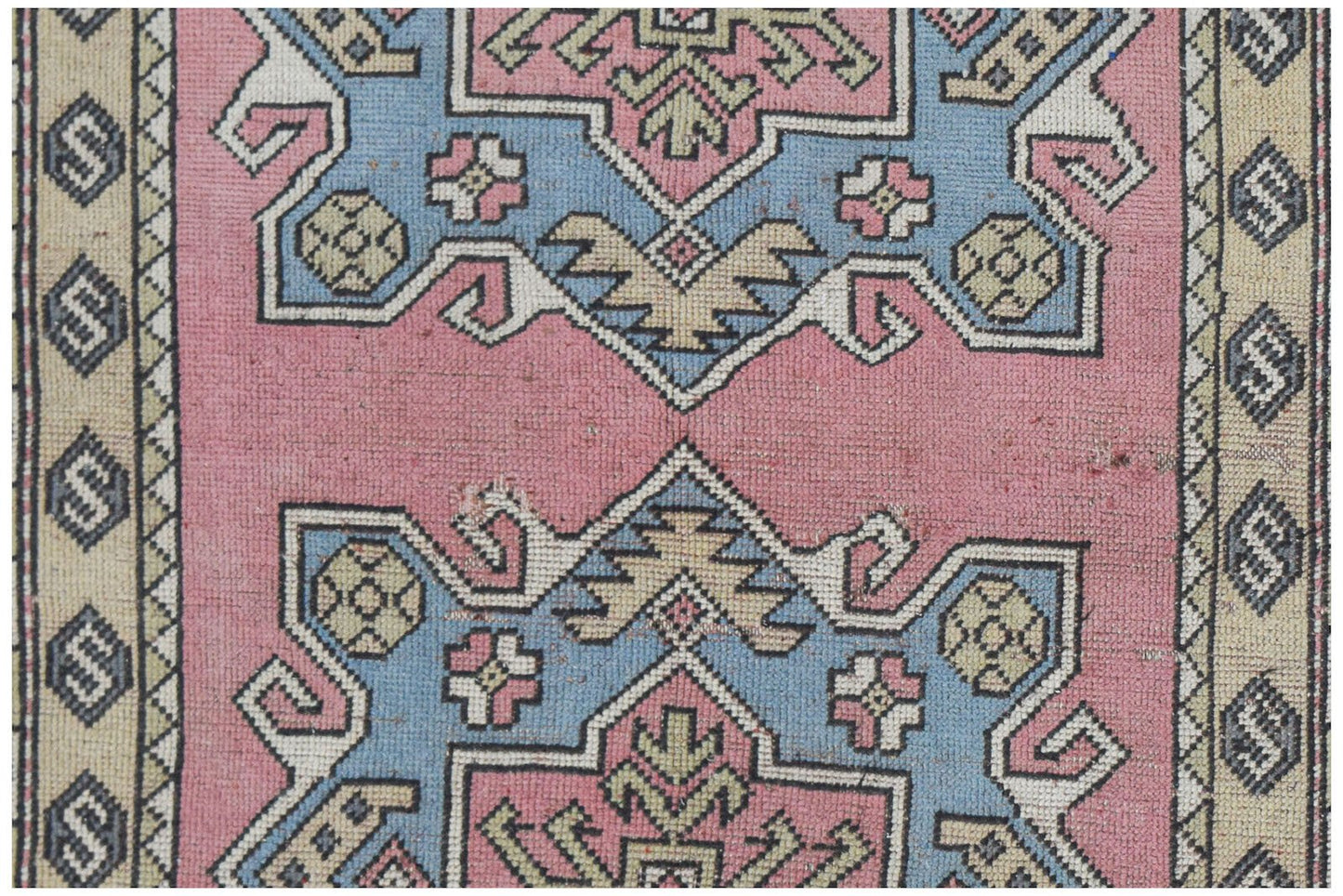 A vintage handwoven Turkish Milas rug featuring geometric patterns in pink, blue, and beige.