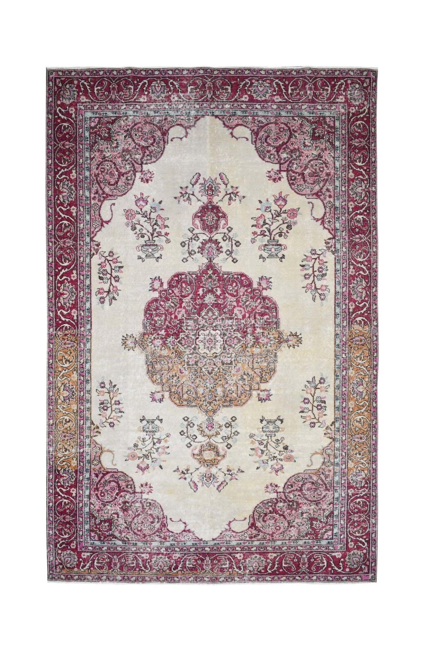A vintage handmade Turkish rug featuring a central medallion and floral motifs in pink and cream.