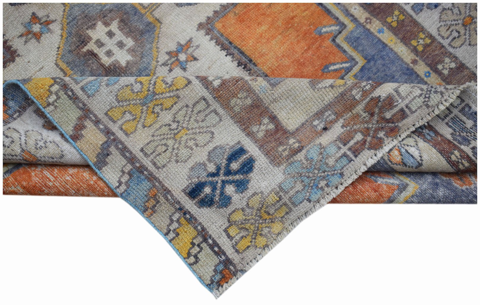 A vintage handwoven Turkish Taspinar rug featuring geometric patterns in orange, blue, and yellow.
