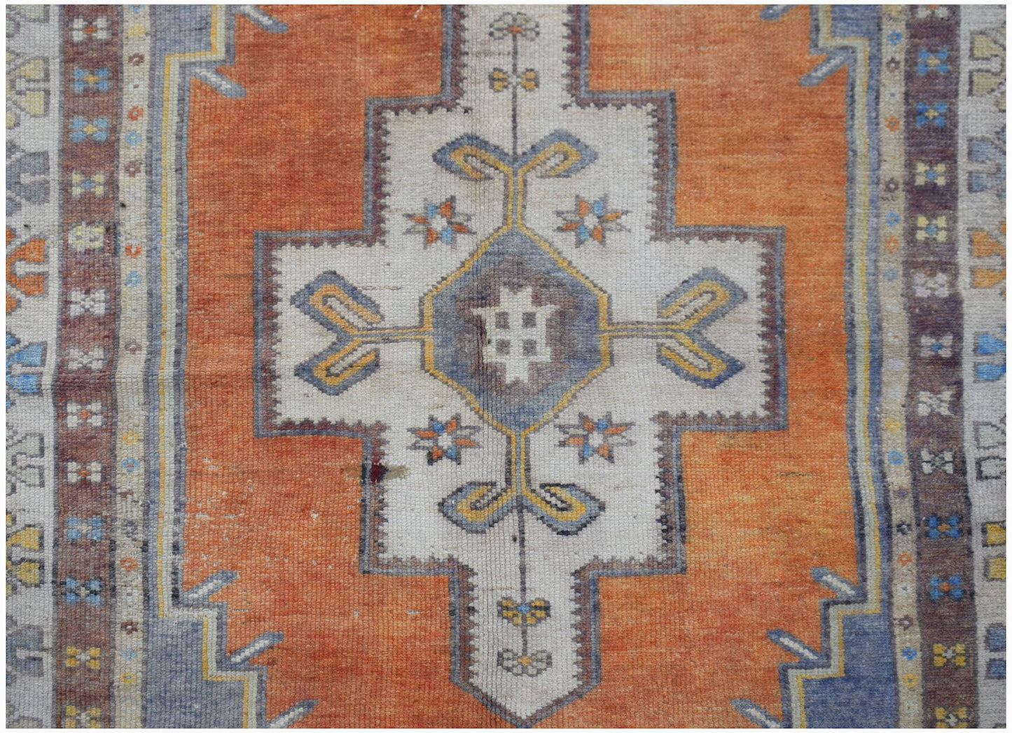 A vintage handwoven Turkish Taspinar rug featuring a geometric medallion on an orange field.