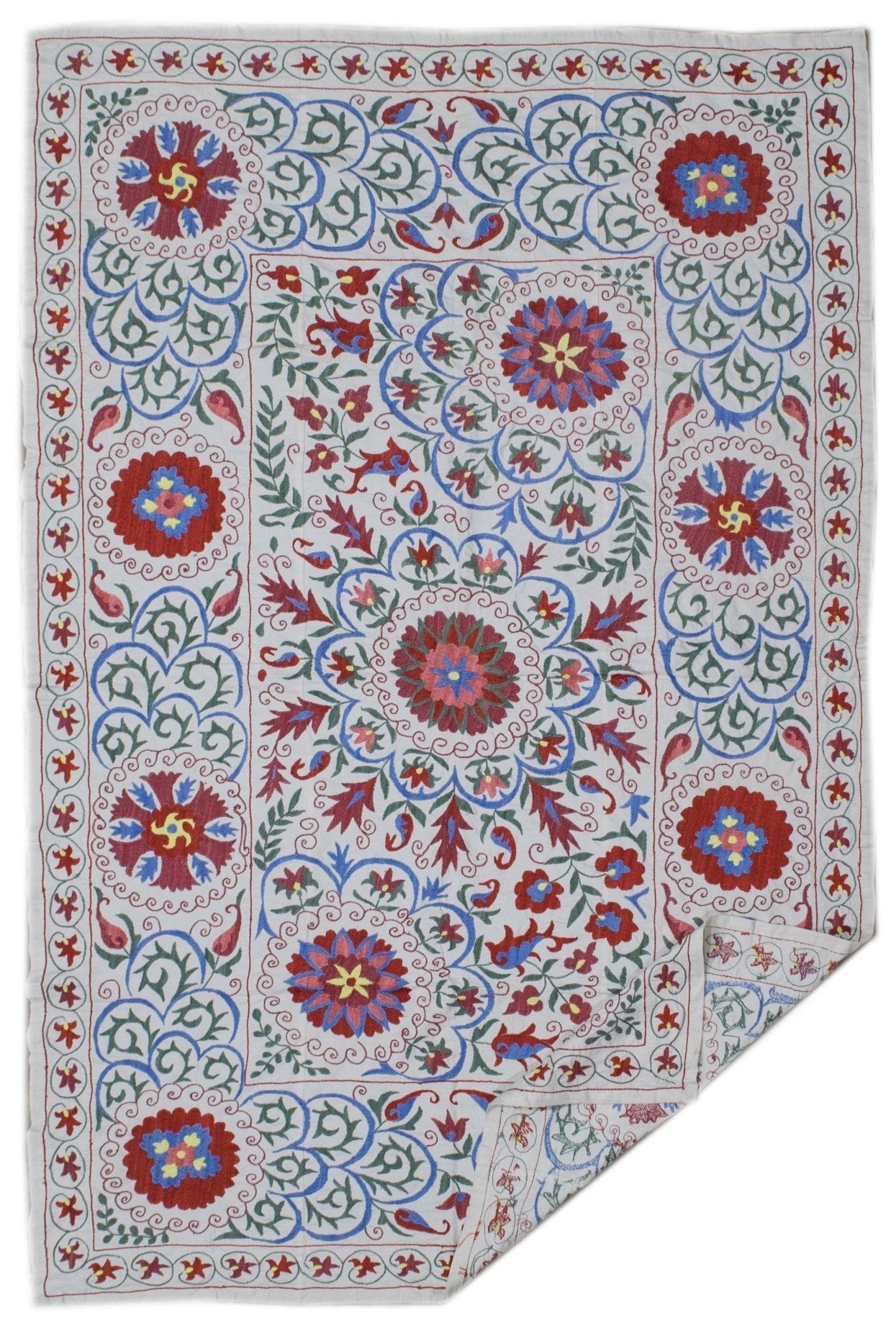 Handmade Uzbek suzani featuring intricate floral embroidery in red, blue, and yellow on cotton.