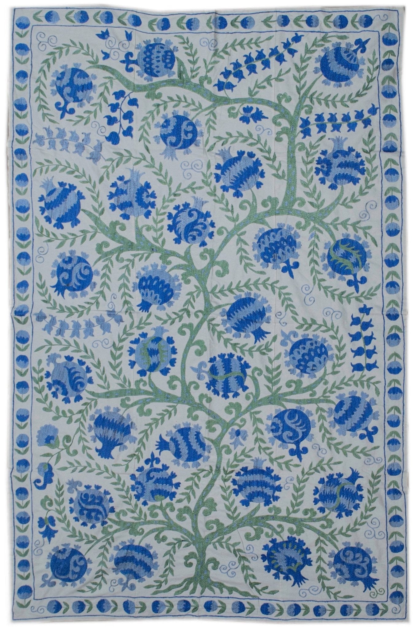 Handmade Uzbek suzani featuring blue pomegranate embroidery on a white cotton base.