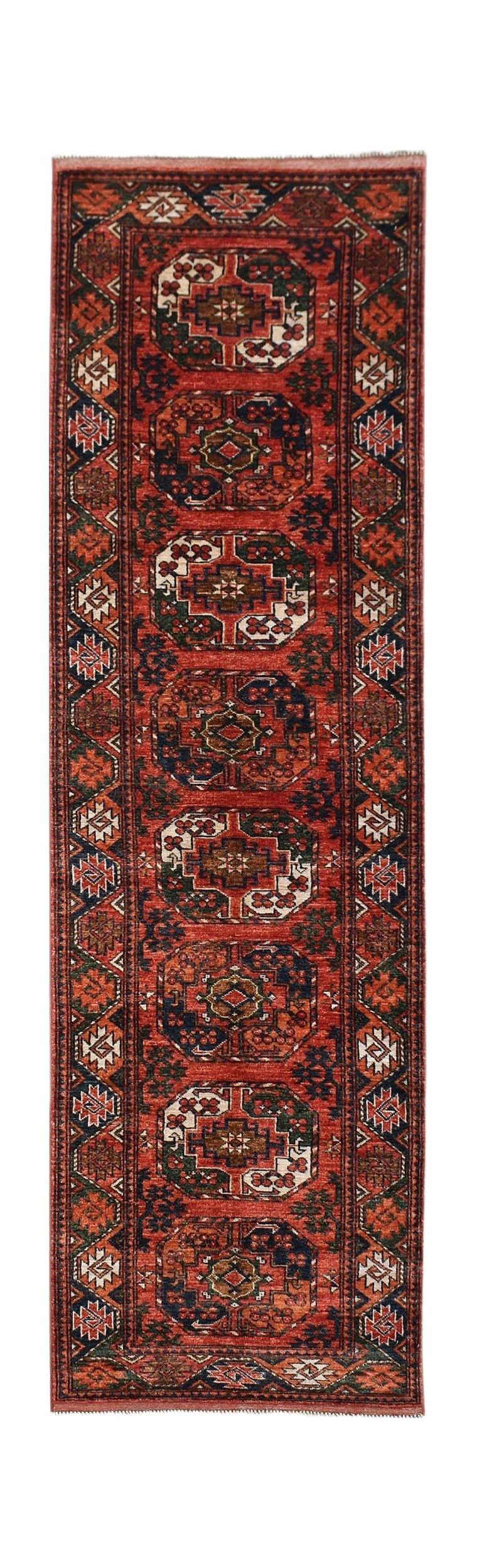 A handmade Afghan Chobi runner rug featuring repeating geometric medallions in red and navy tones.
