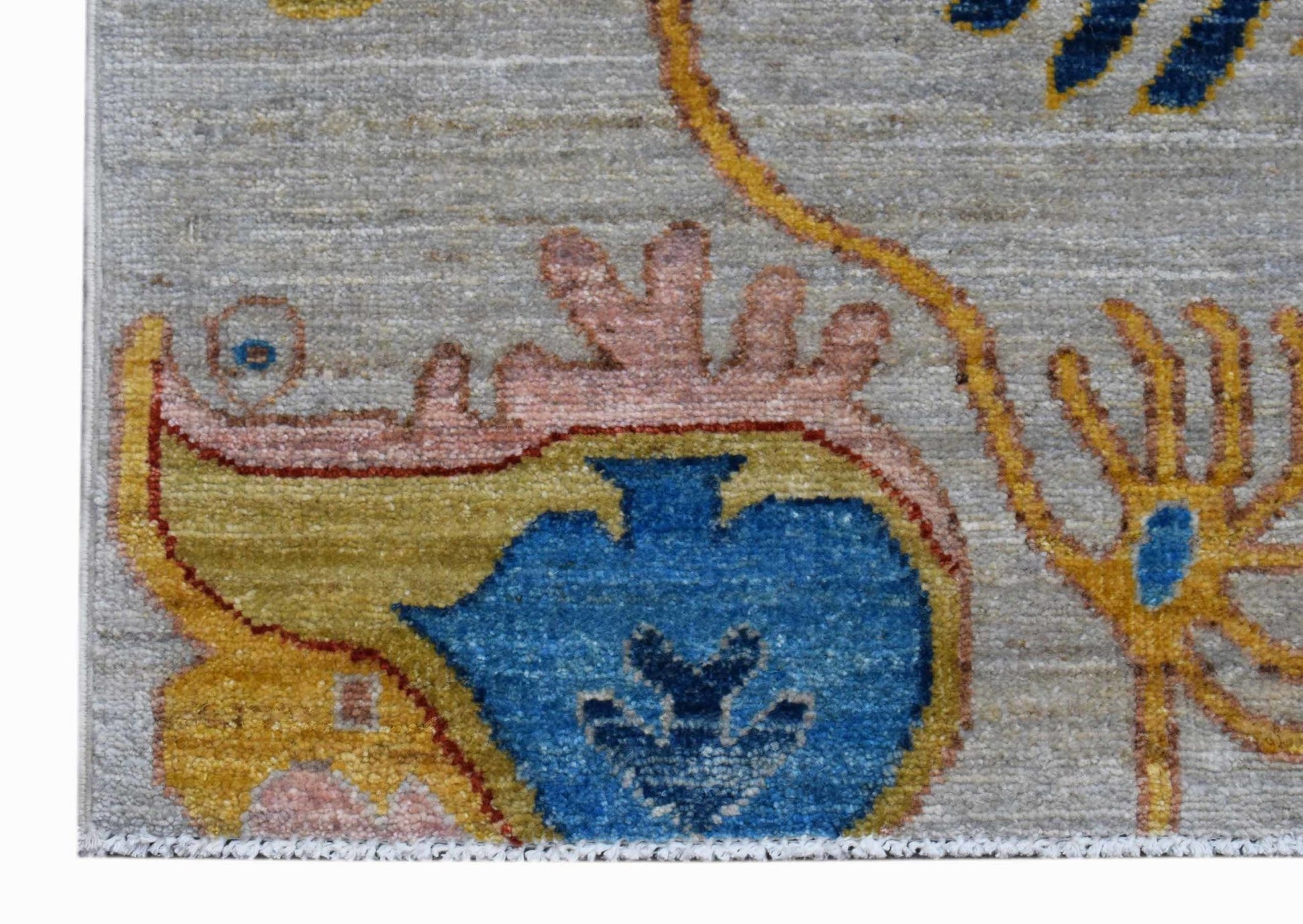 A close-up of an Afghan Chobi runner featuring a blue floral motif on a grey wool background.