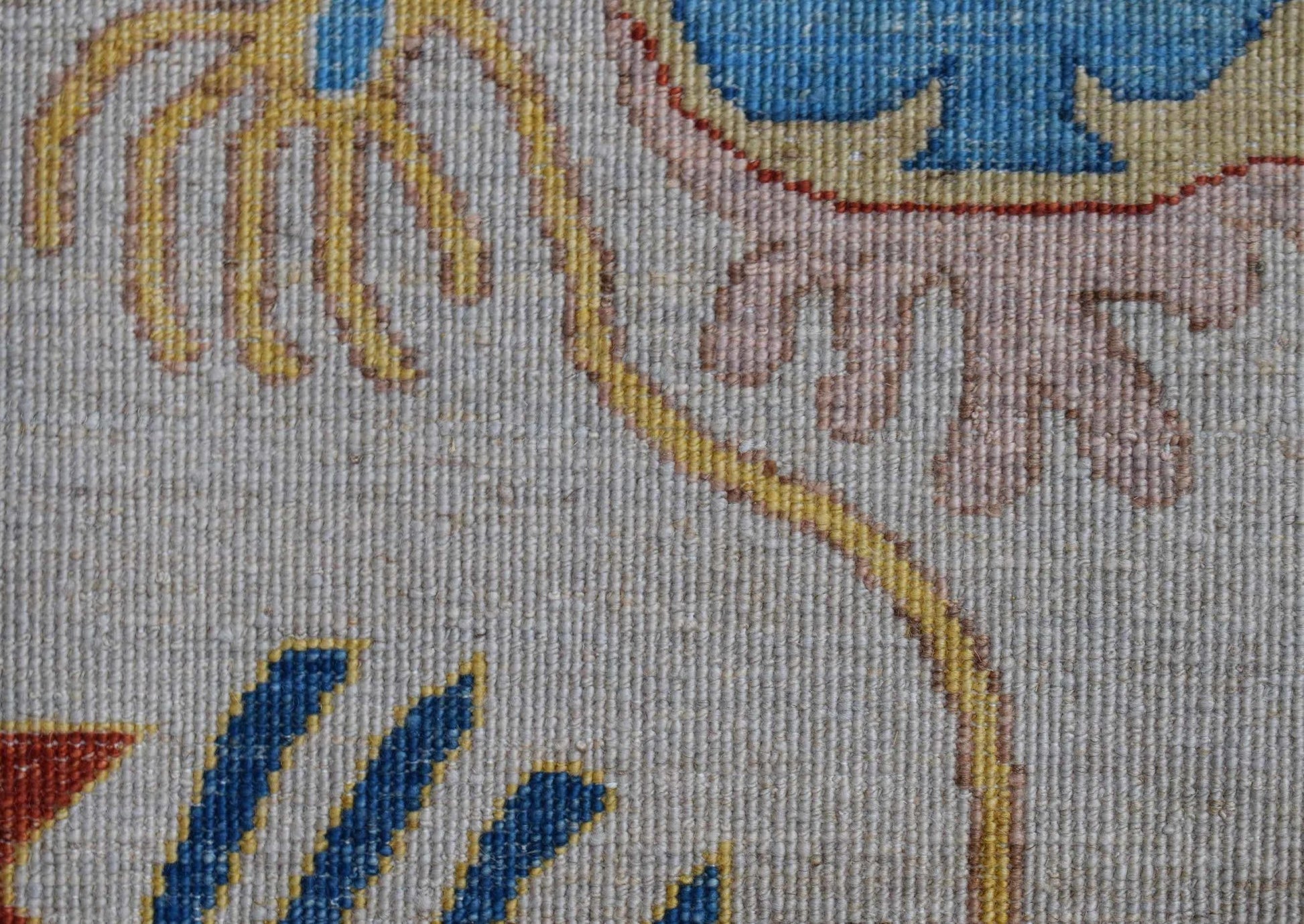 A close-up of an Afghan Chobi runner featuring intricate floral patterns in blue, yellow, and pink.