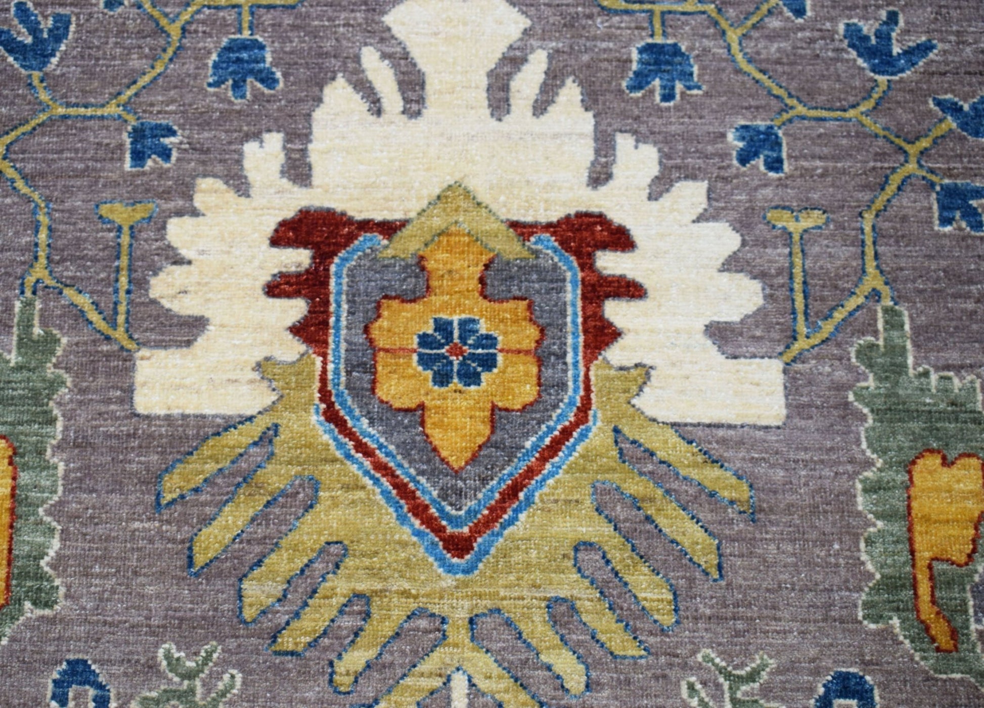A handwoven Afghan Chobi runner featuring a central floral medallion in earthy tones.