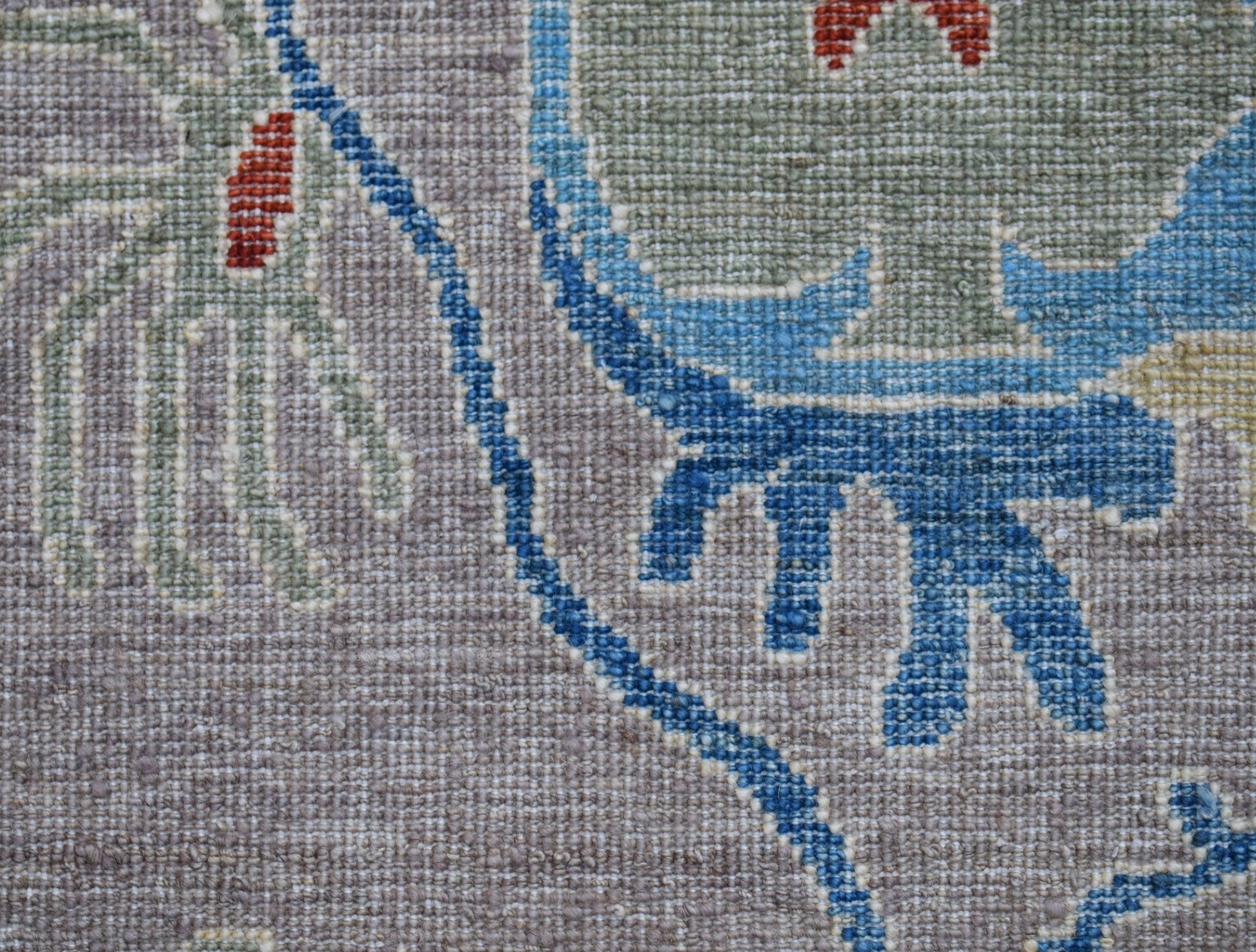 A close-up of a handwoven Afghan Chobi runner featuring intricate floral patterns in wool.