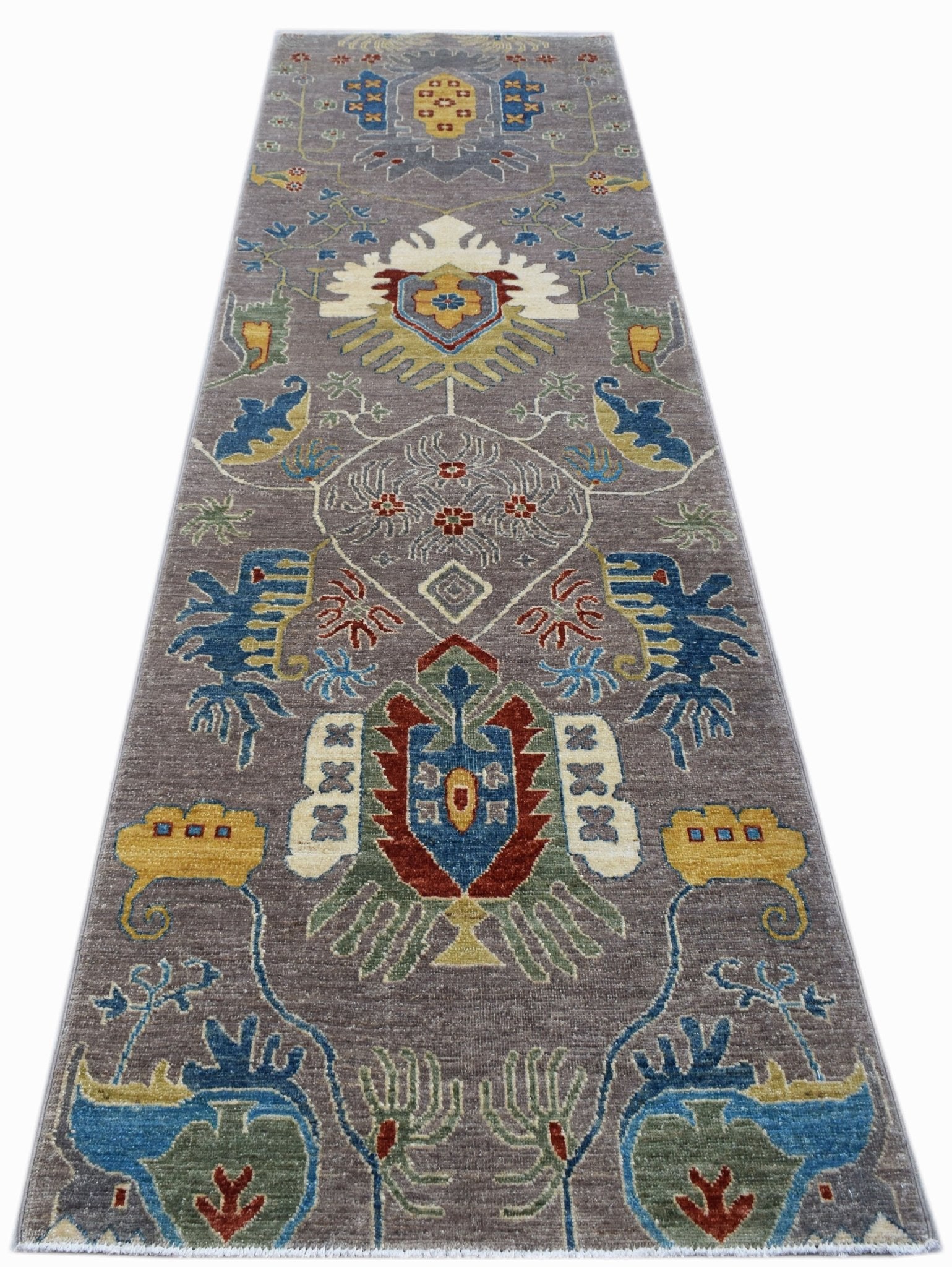 A handwoven Afghan Chobi runner rug featuring traditional floral motifs in earthy tones.