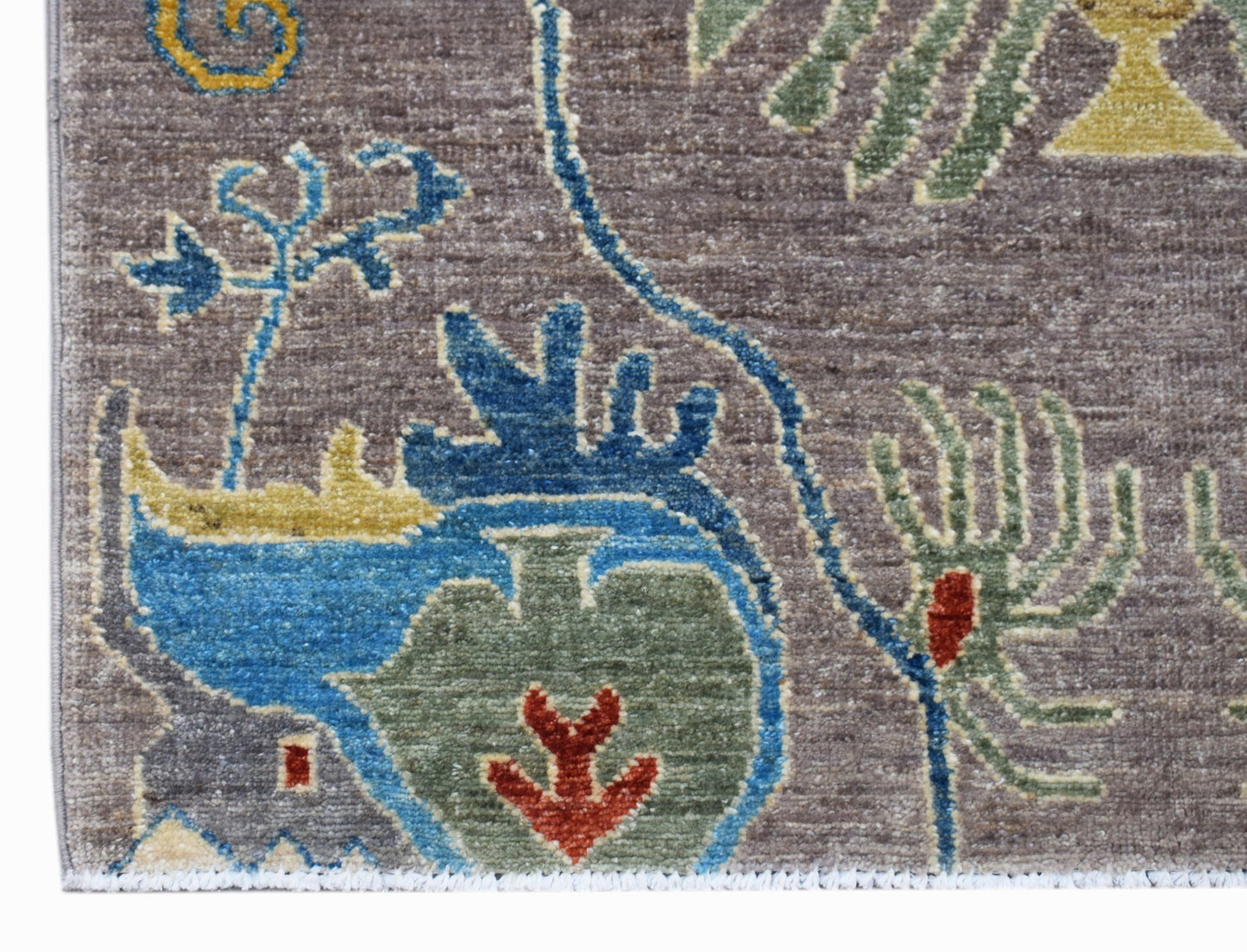 A close-up of an Afghan Chobi runner featuring intricate floral and vase motifs in blue, green, and red.