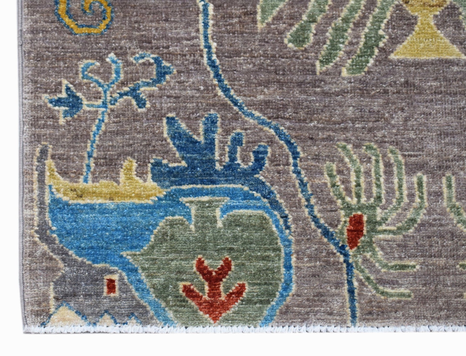 A close-up of an Afghan Chobi runner featuring intricate floral and vase motifs in blue, green, and red.