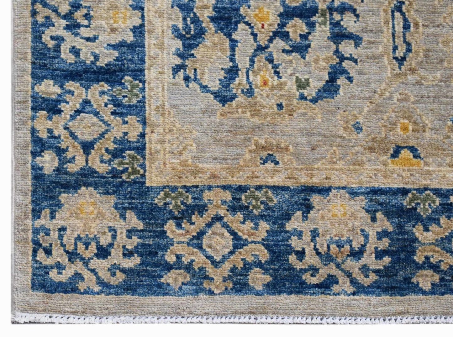 A handwoven Afghan Chobi runner featuring a blue border with floral motifs and a beige center.