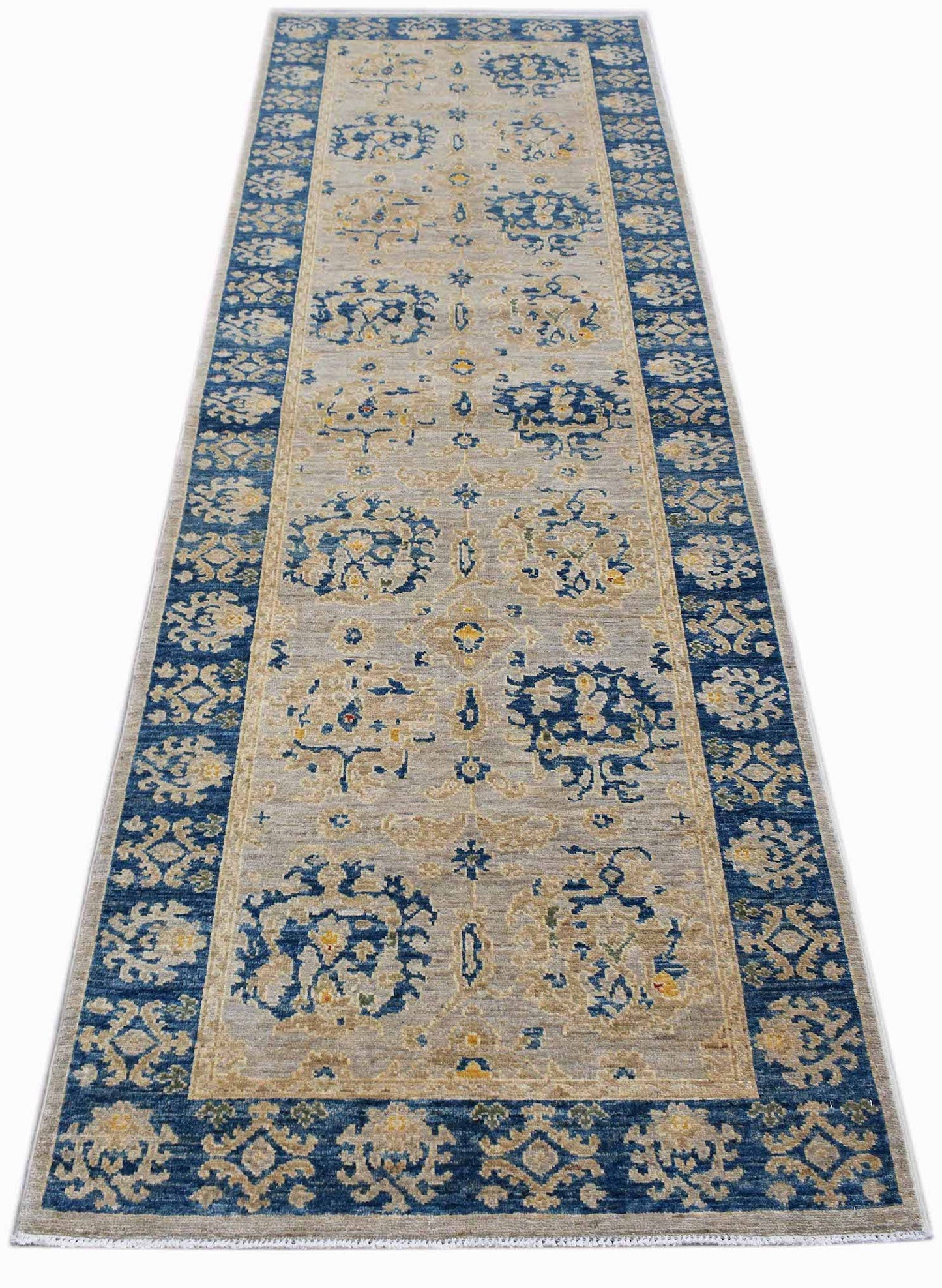 A handmade Afghan Chobi runner rug featuring blue and beige floral patterns on a light grey field.