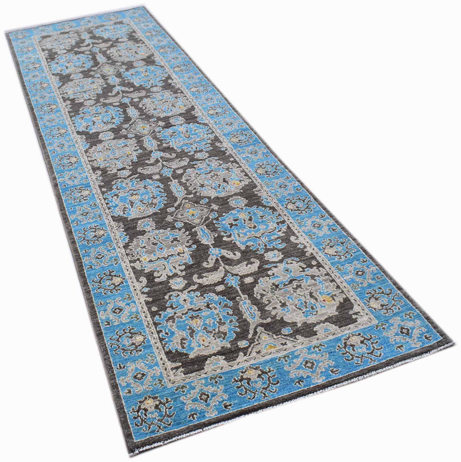 An Afghan Chobi runner rug featuring a dark brown field with blue and grey floral patterns.