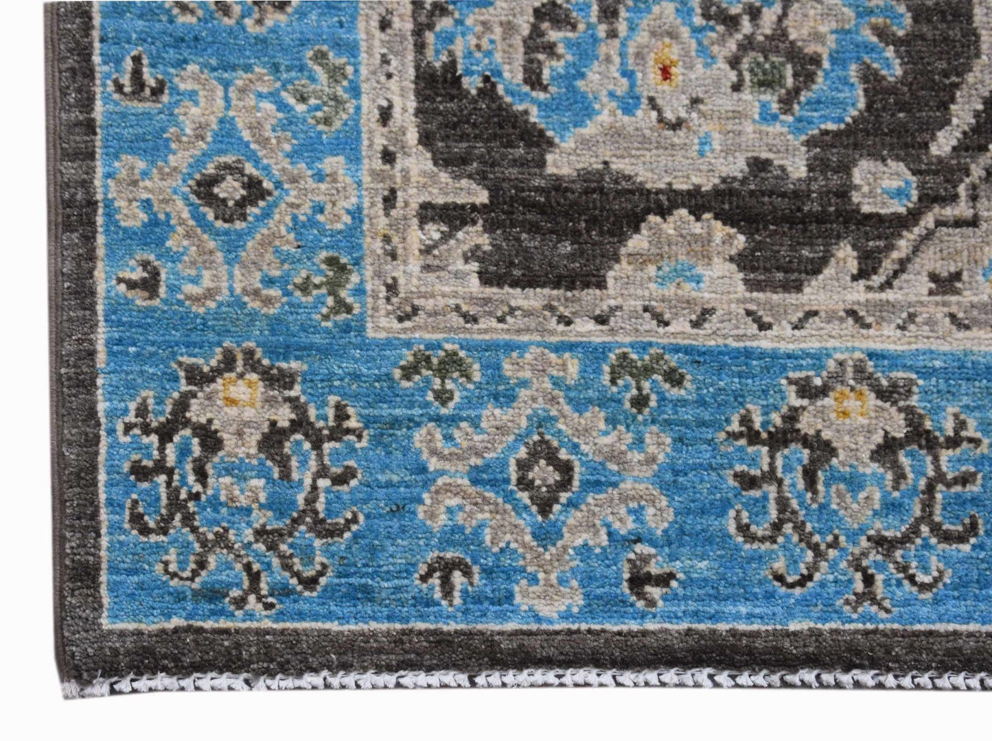 A close-up of an Afghan Chobi runner featuring intricate floral patterns in blue, grey, and black.