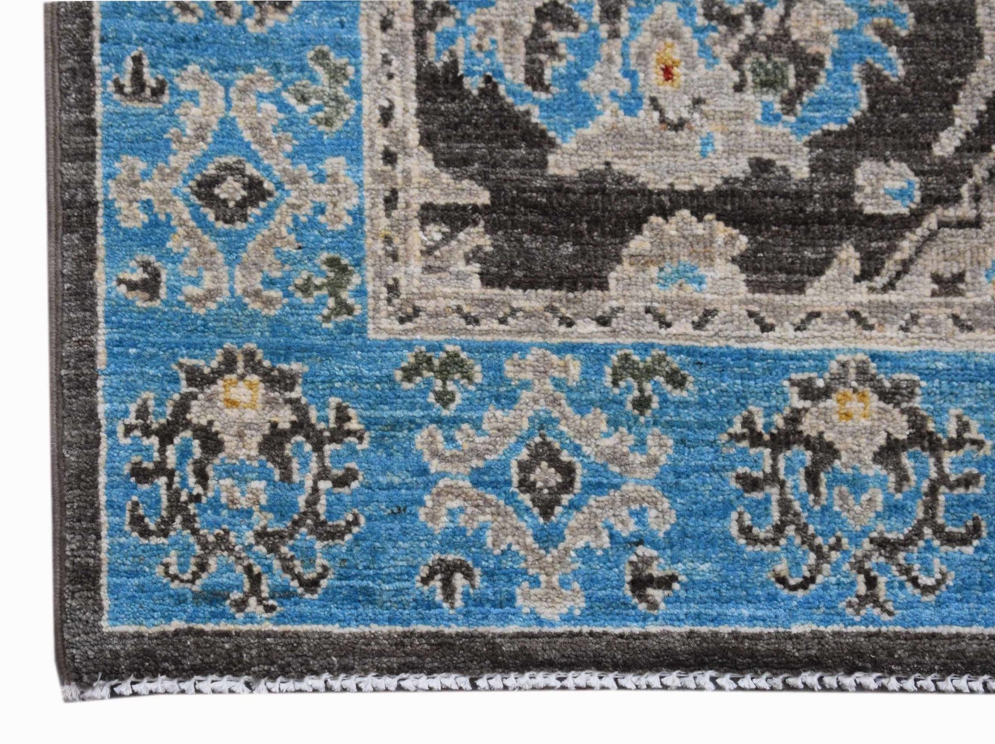 A close-up of an Afghan Chobi runner featuring intricate floral patterns in blue, grey, and black.