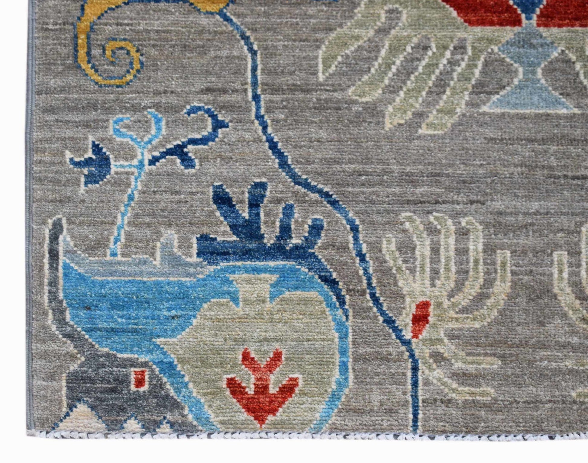 A handmade Afghan Chobi runner featuring intricate floral patterns in blue, red, and grey wool.