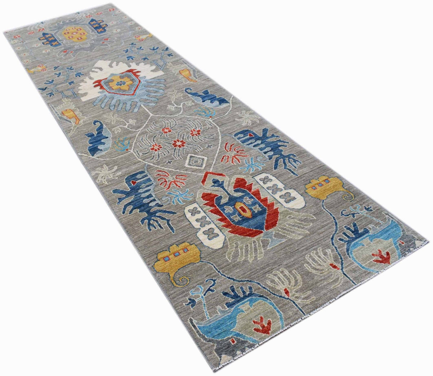 A handmade Afghan Chobi runner rug featuring a grey field with colorful traditional floral motifs.