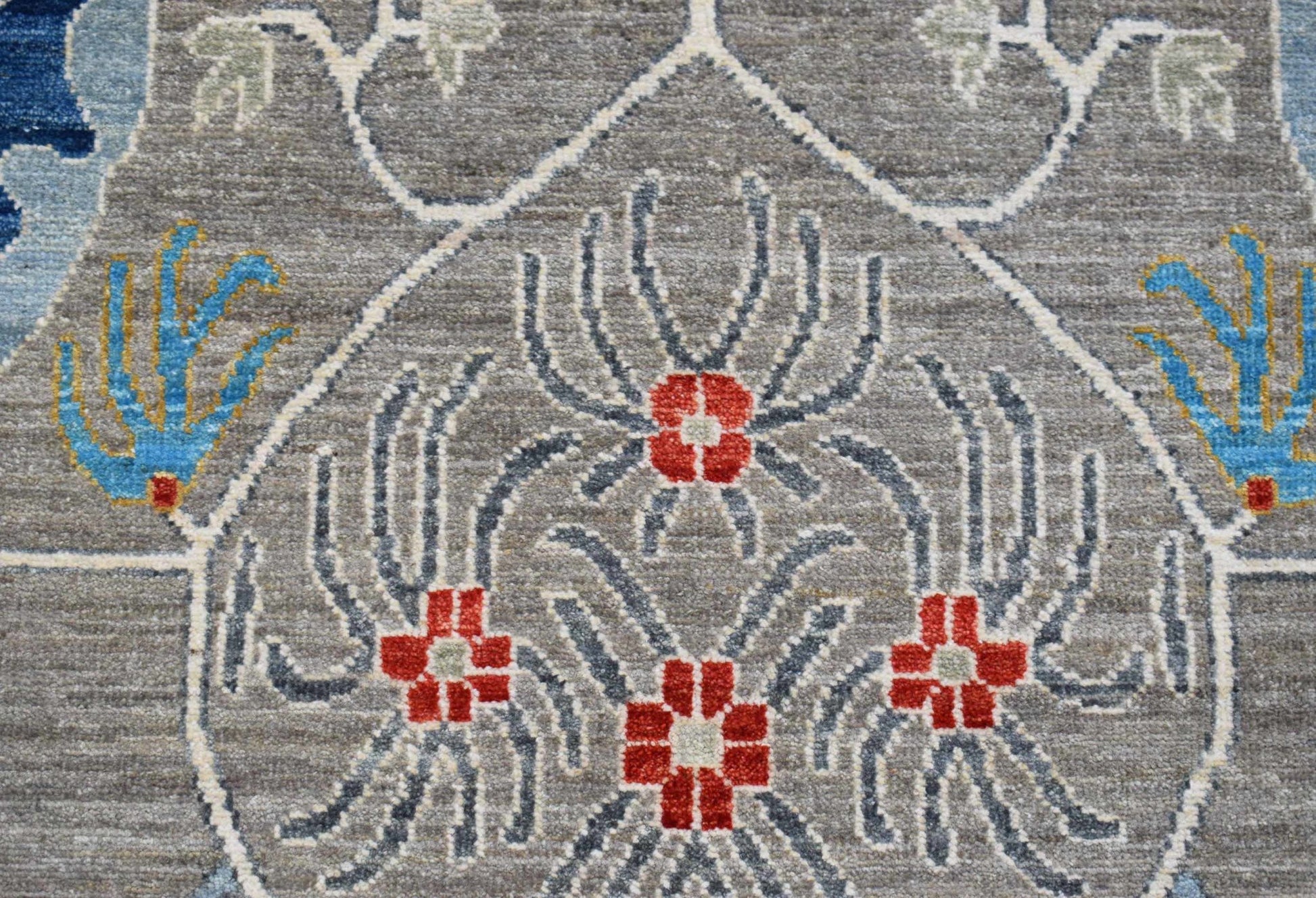 A handwoven Afghan Chobi runner featuring a grey field with red floral motifs and blue accents.