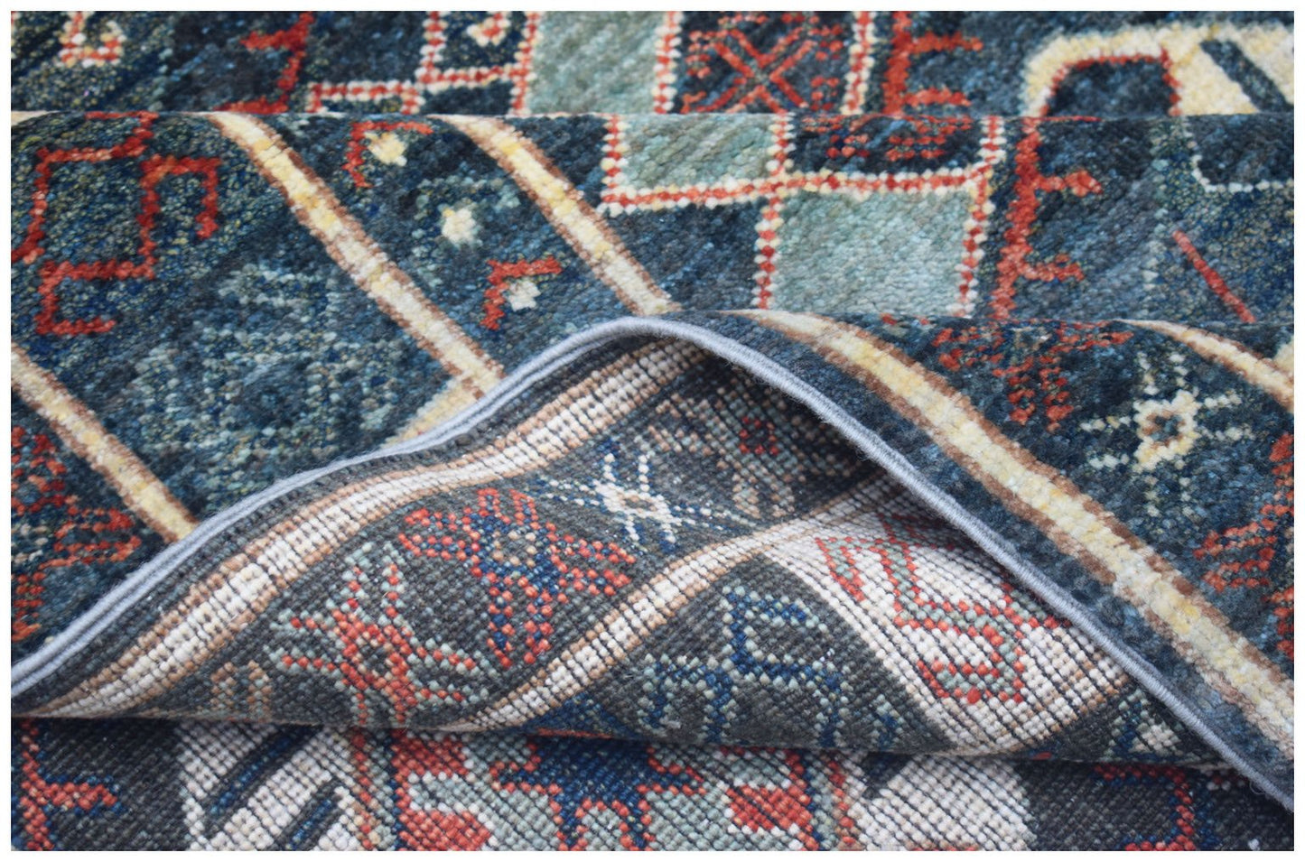 A close-up view of a handwoven Afghan Chobi runner featuring a geometric pattern in blue and red.