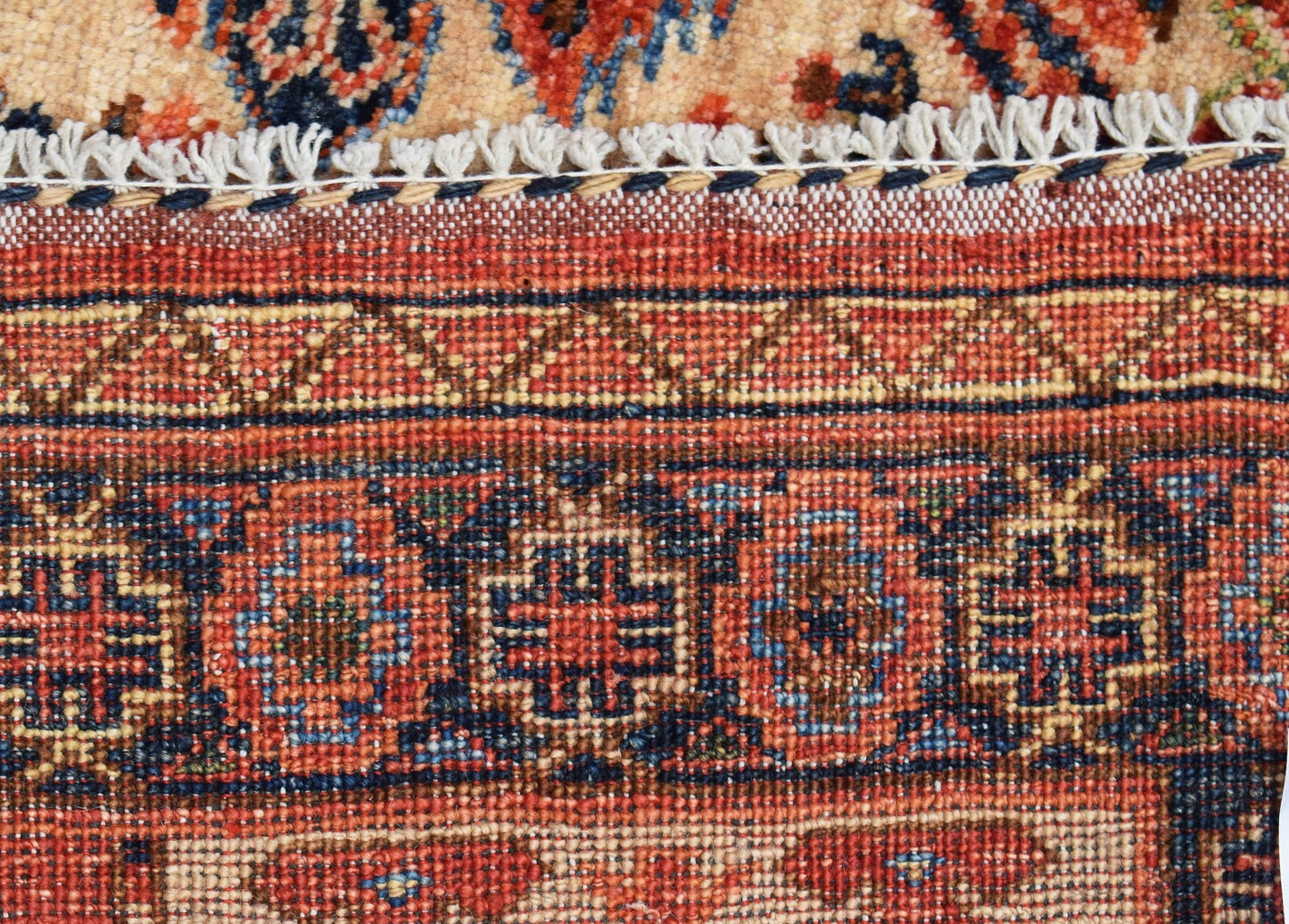A close-up of a handwoven Afghan Chobi rug featuring intricate geometric patterns in warm tones.