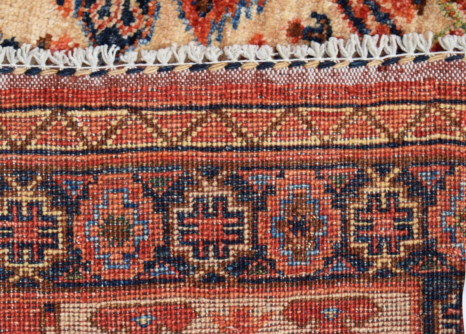 A close-up of a handwoven Afghan Chobi rug featuring intricate geometric patterns in warm tones.