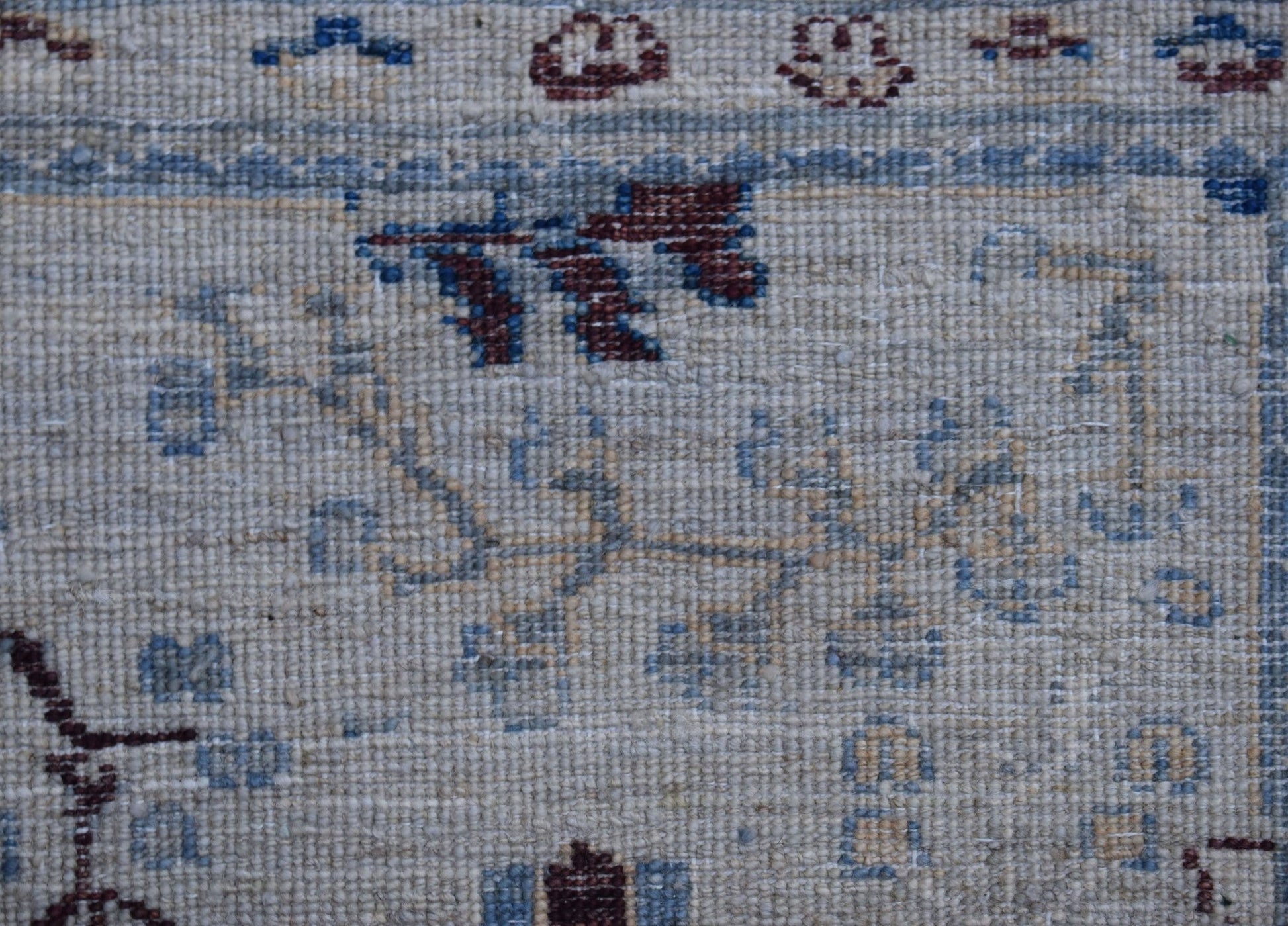 A close-up of a handwoven Afghan Chobi rug featuring traditional floral patterns in wool.